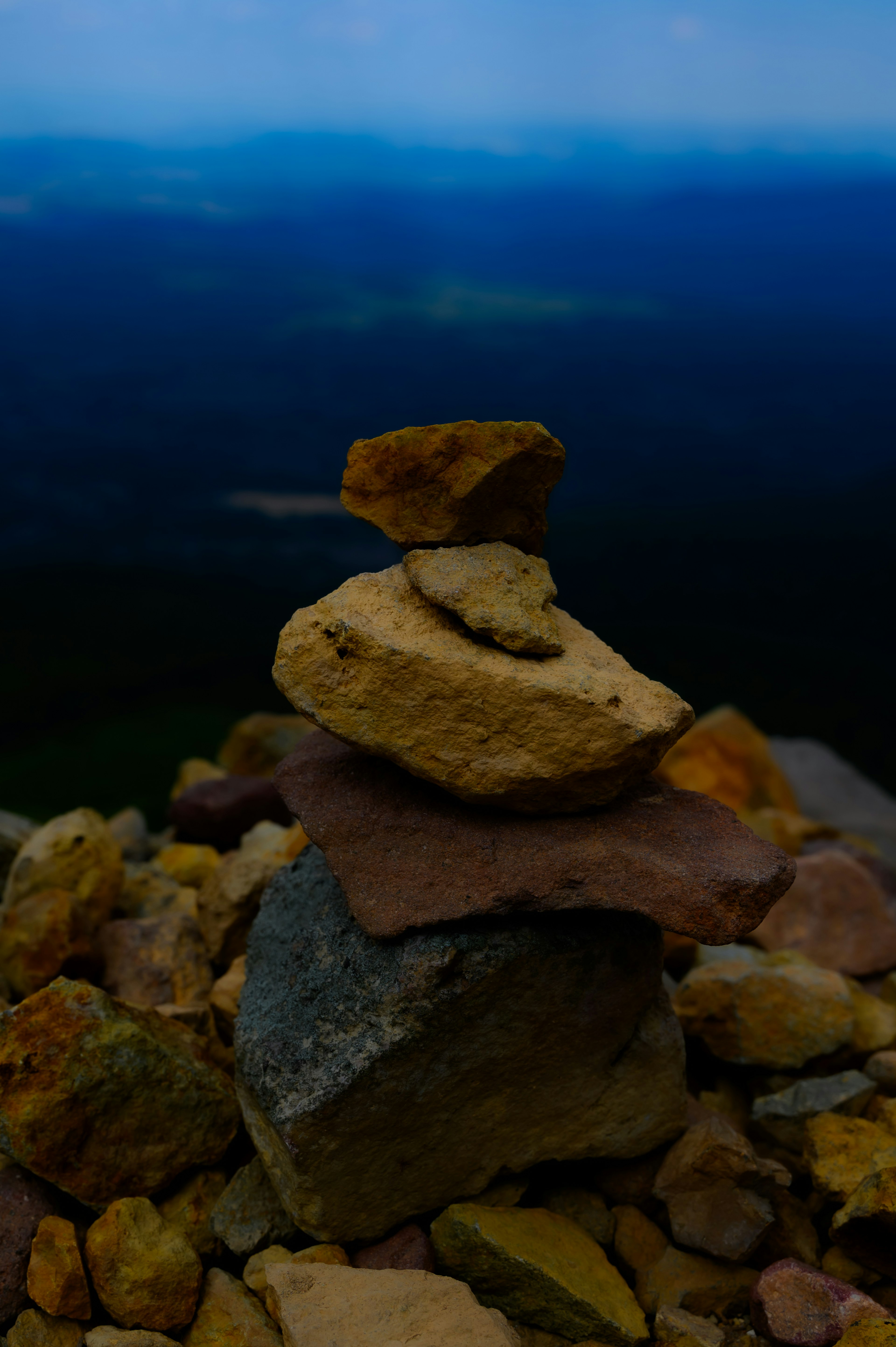 Montón de piedras en la cima de una montaña con cielo azul