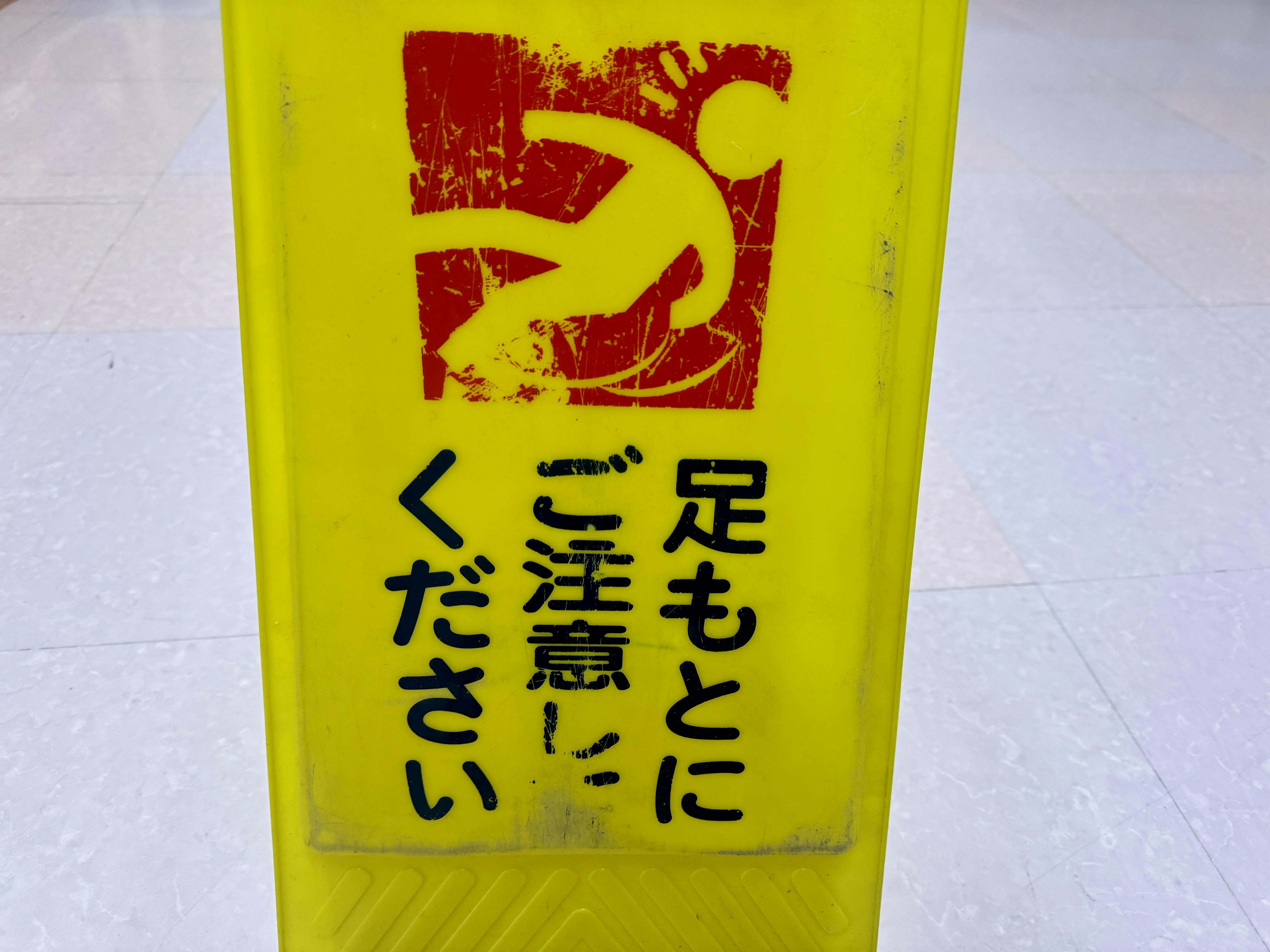 Yellow caution sign with red text saying be careful of your feet