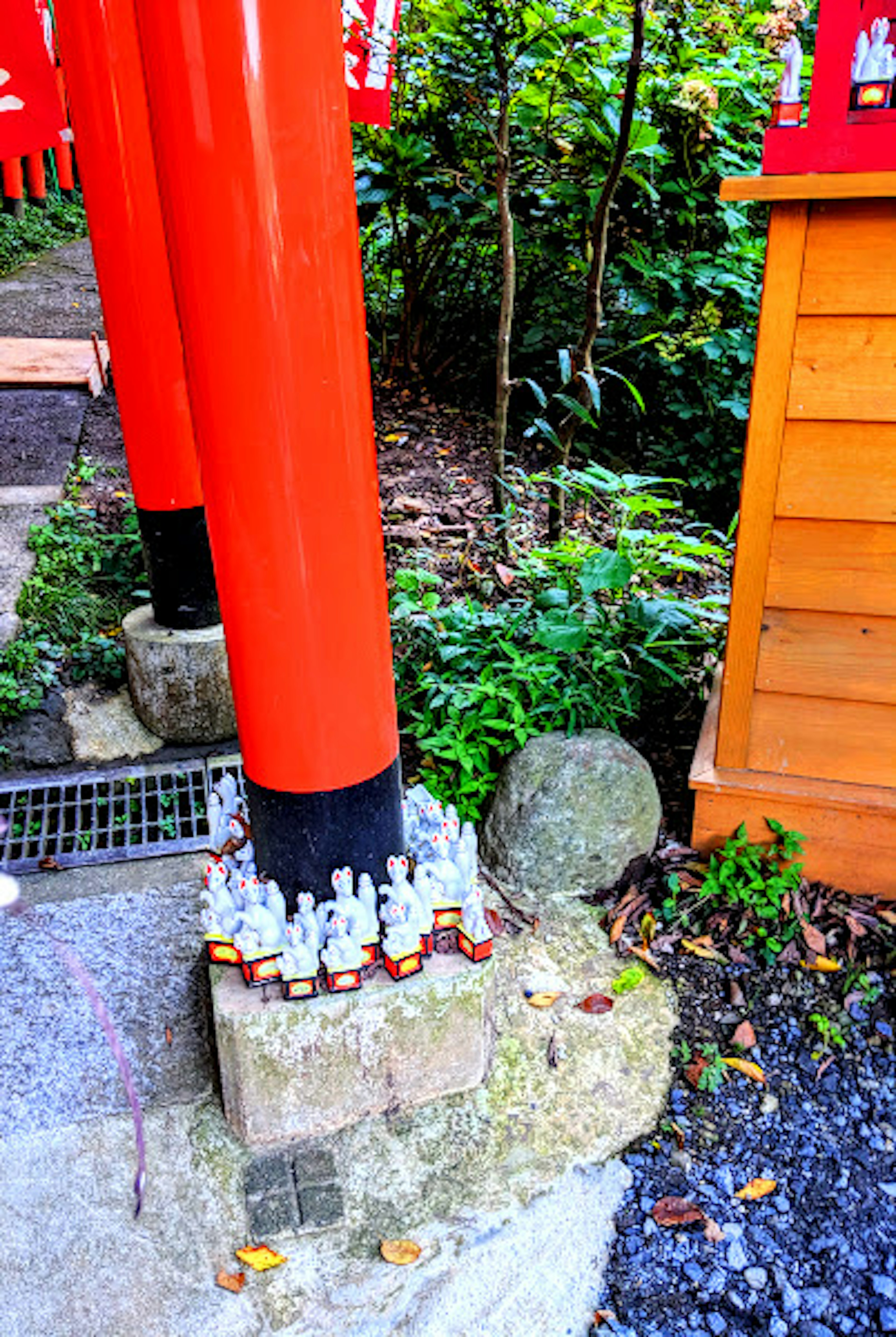 Ansicht von kleinen Statuen, die an der Basis eines roten Torii-Tors angeordnet sind