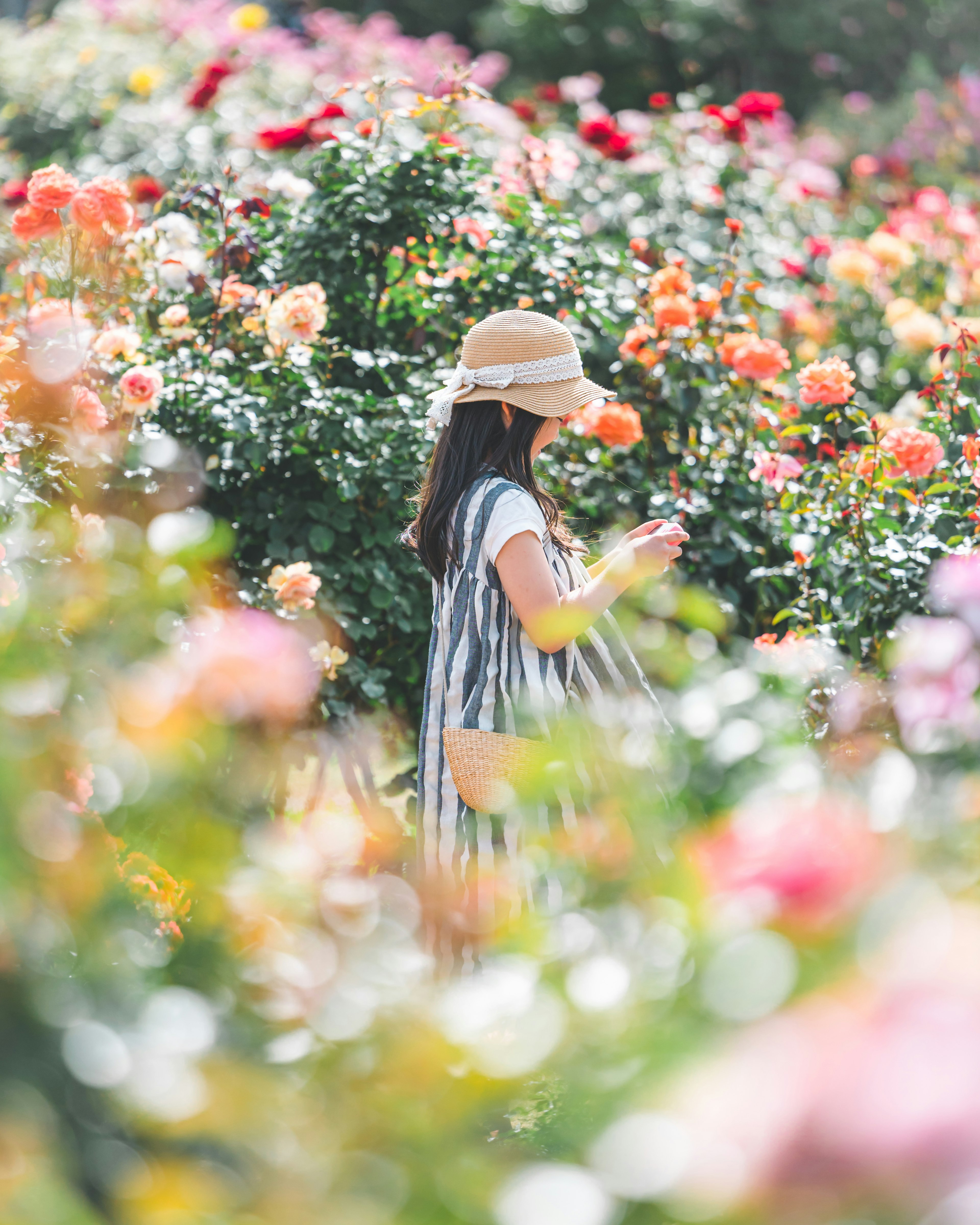 Una ragazza con uno smartphone circondata da rose colorate