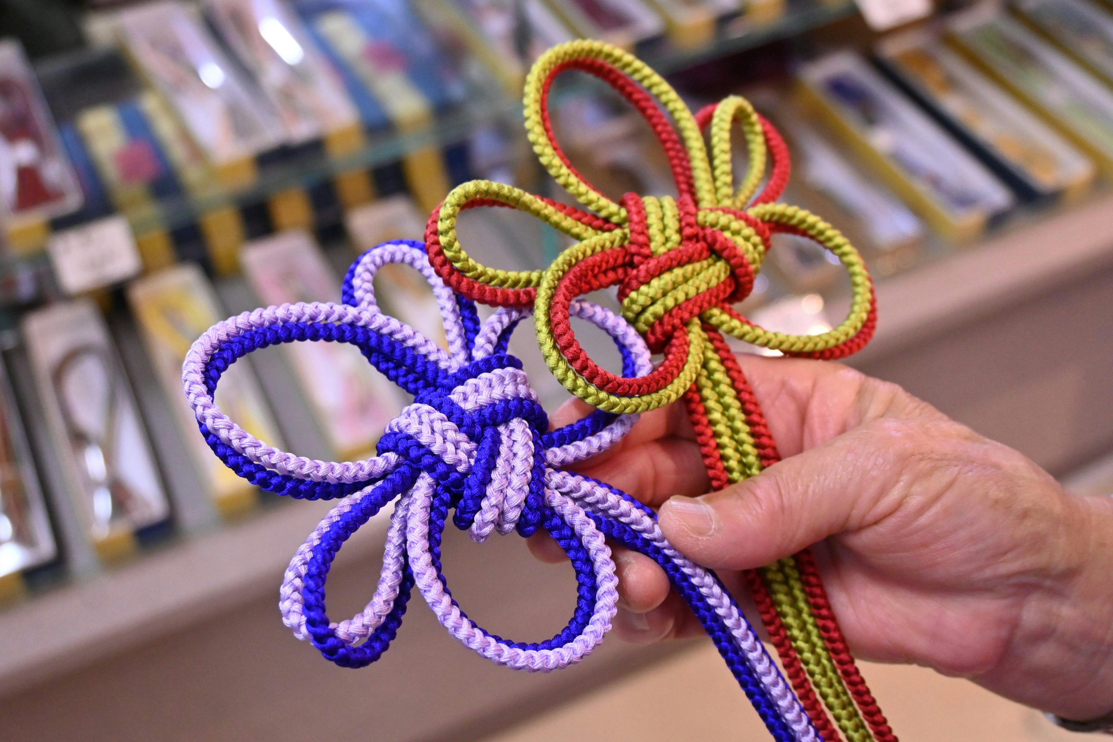 Immagine di una mano che tiene nodi colorati con corde decorative blu e rosse