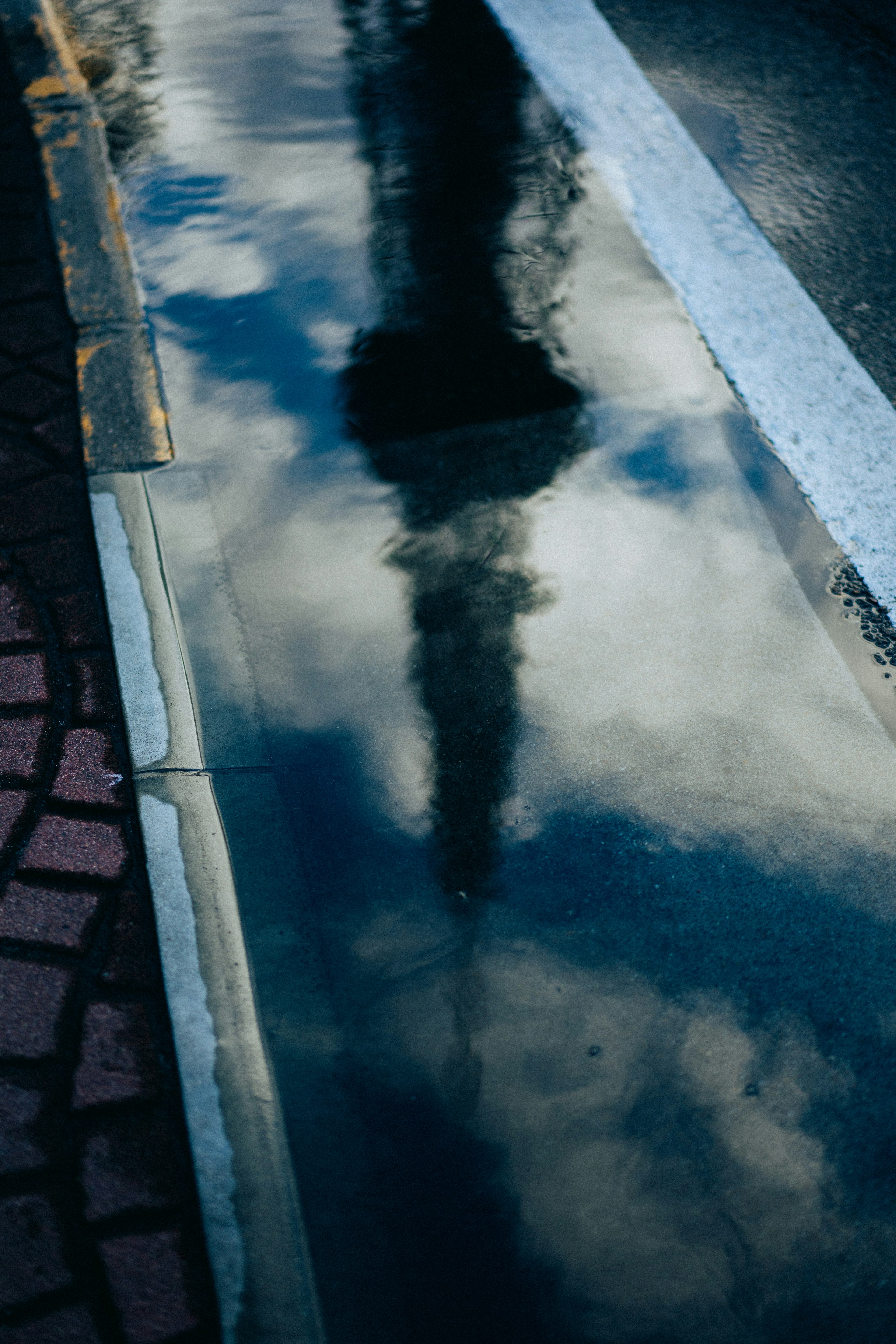 Réflexion des nuages et d'un bâtiment dans une flaque d'eau