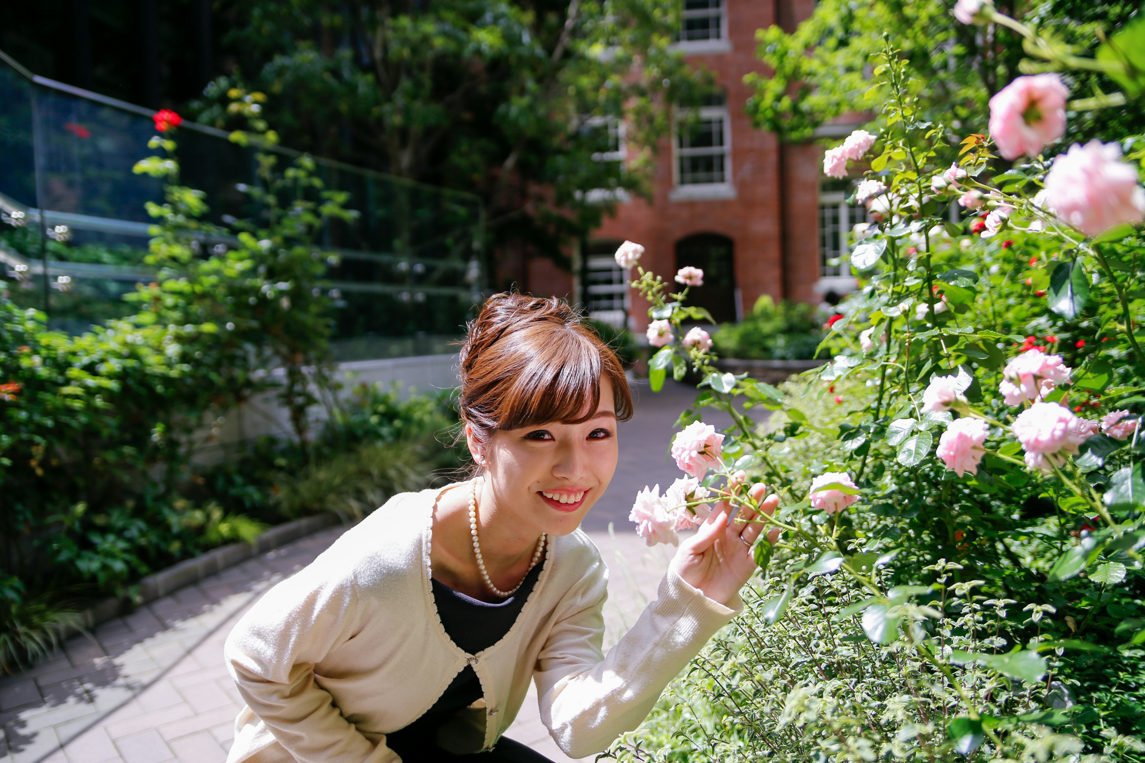 女性が花を手に笑顔でポーズをとっている庭の風景