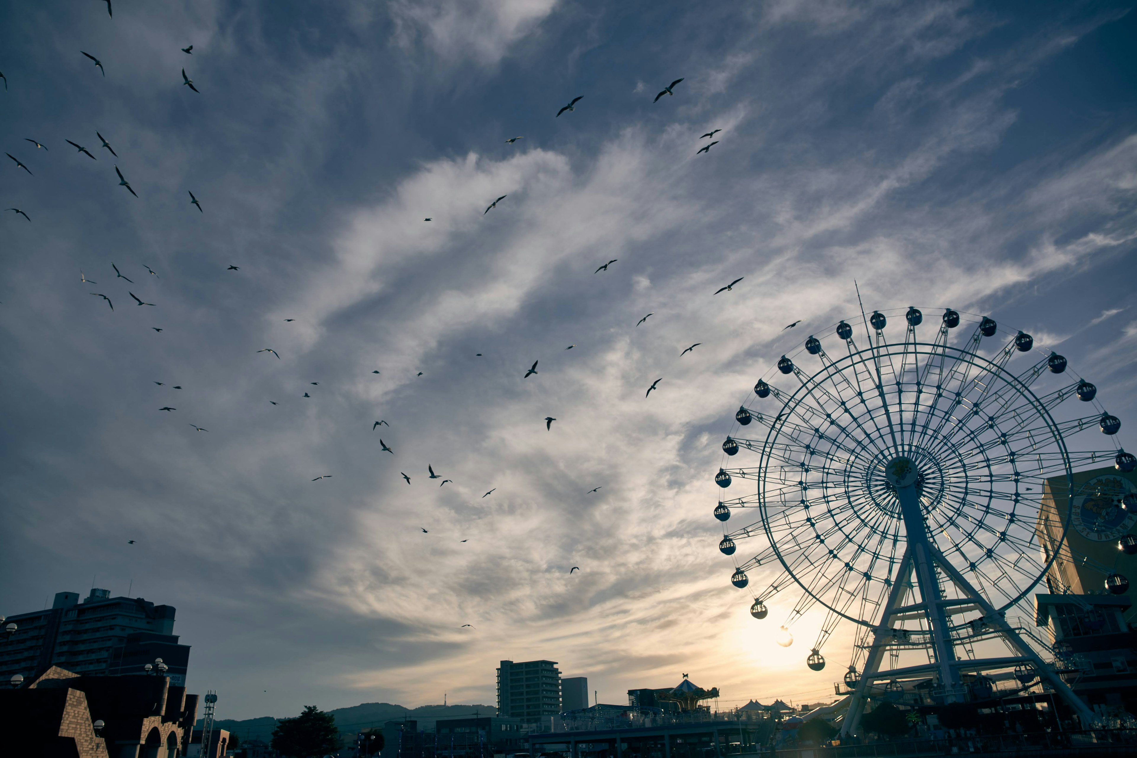 夕暮れの空の下にある観覧車のシルエットと雲