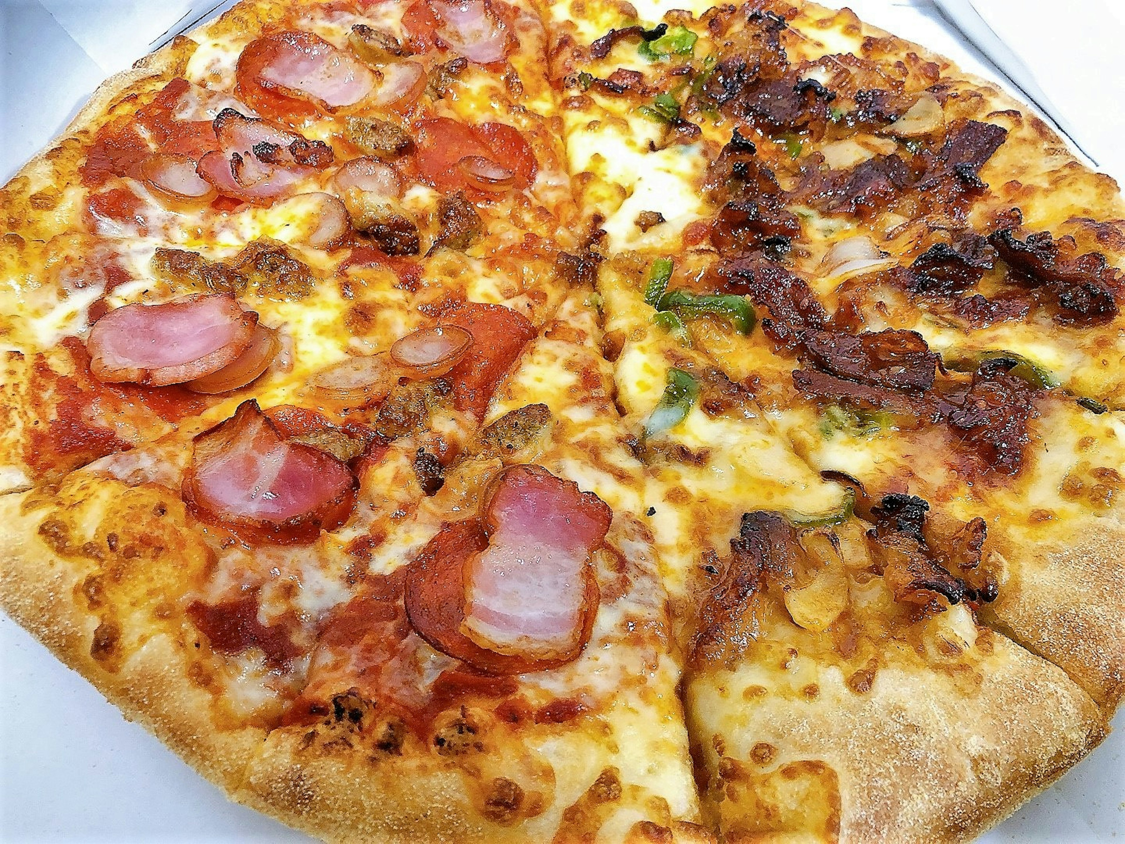 Pizza dengan setengah atas ham dan bacon dan setengah atas daging