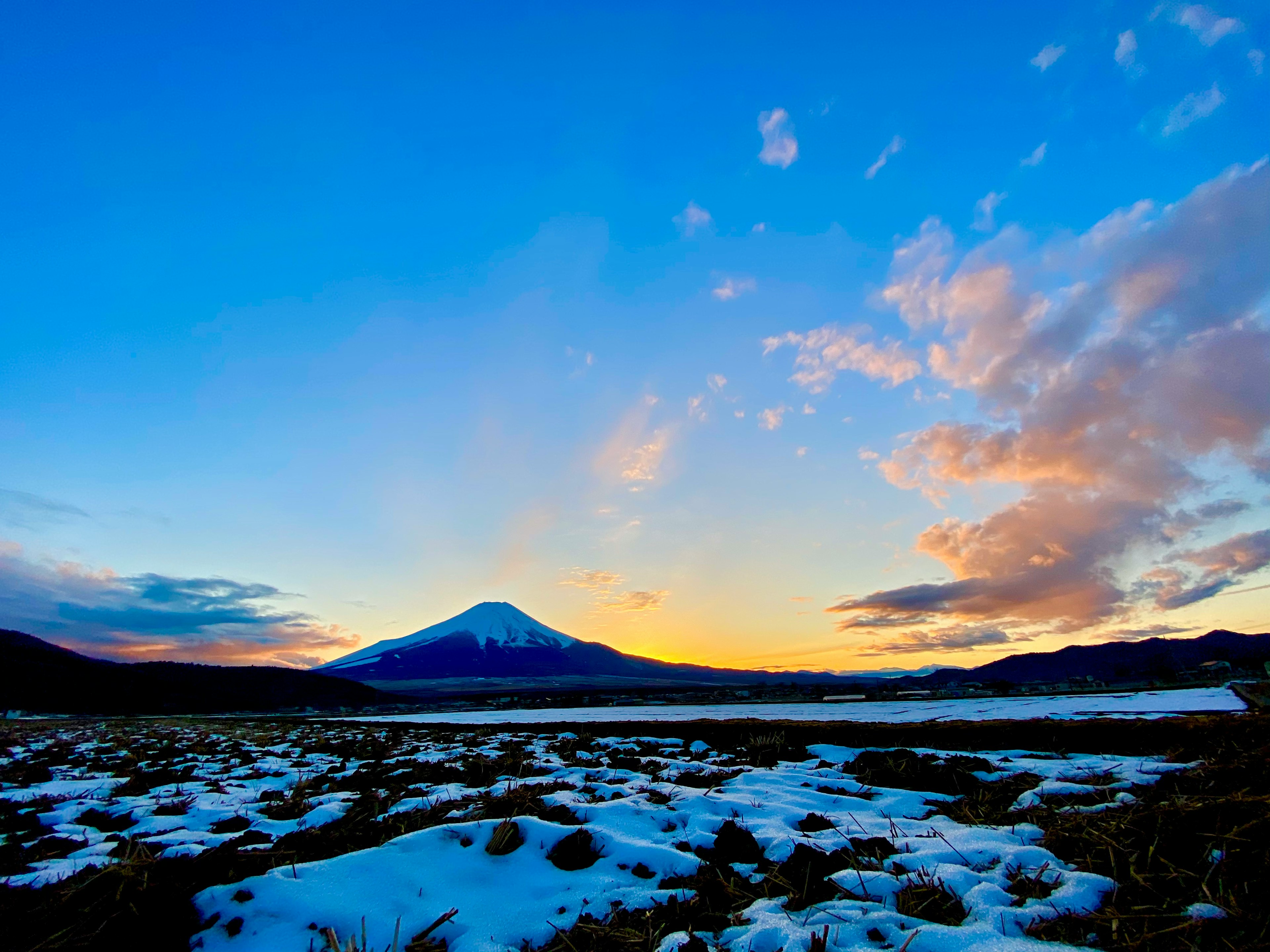 Montagna innevata con cielo blu e tramonto