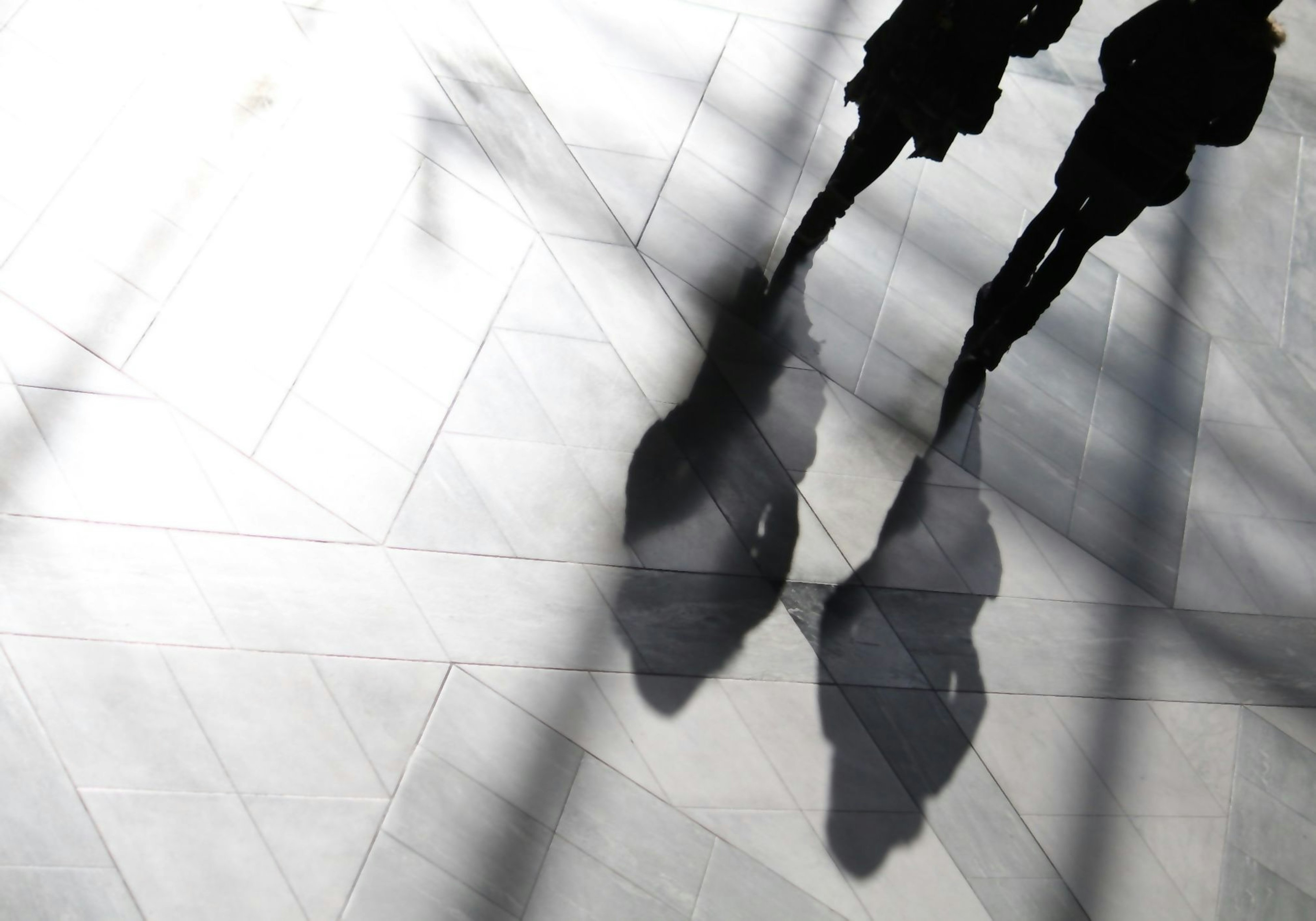 Shadows of two people on a light-colored floor