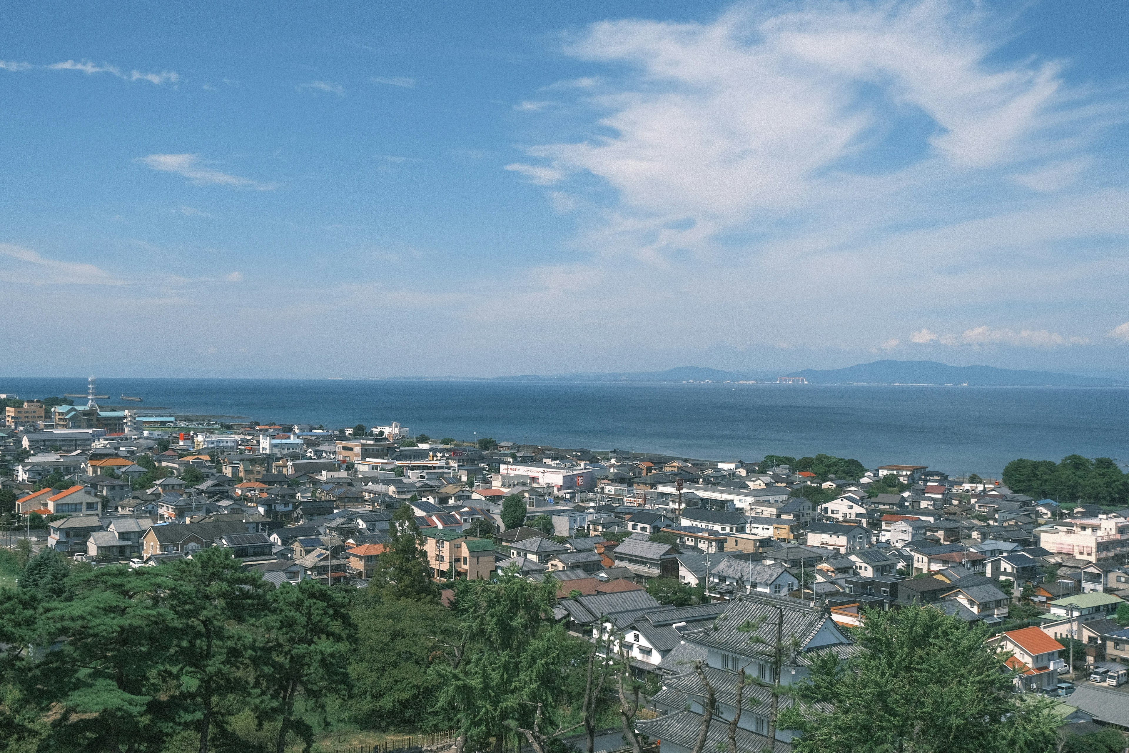 A panoramic view of a coastal town with blue sea and scattered clouds