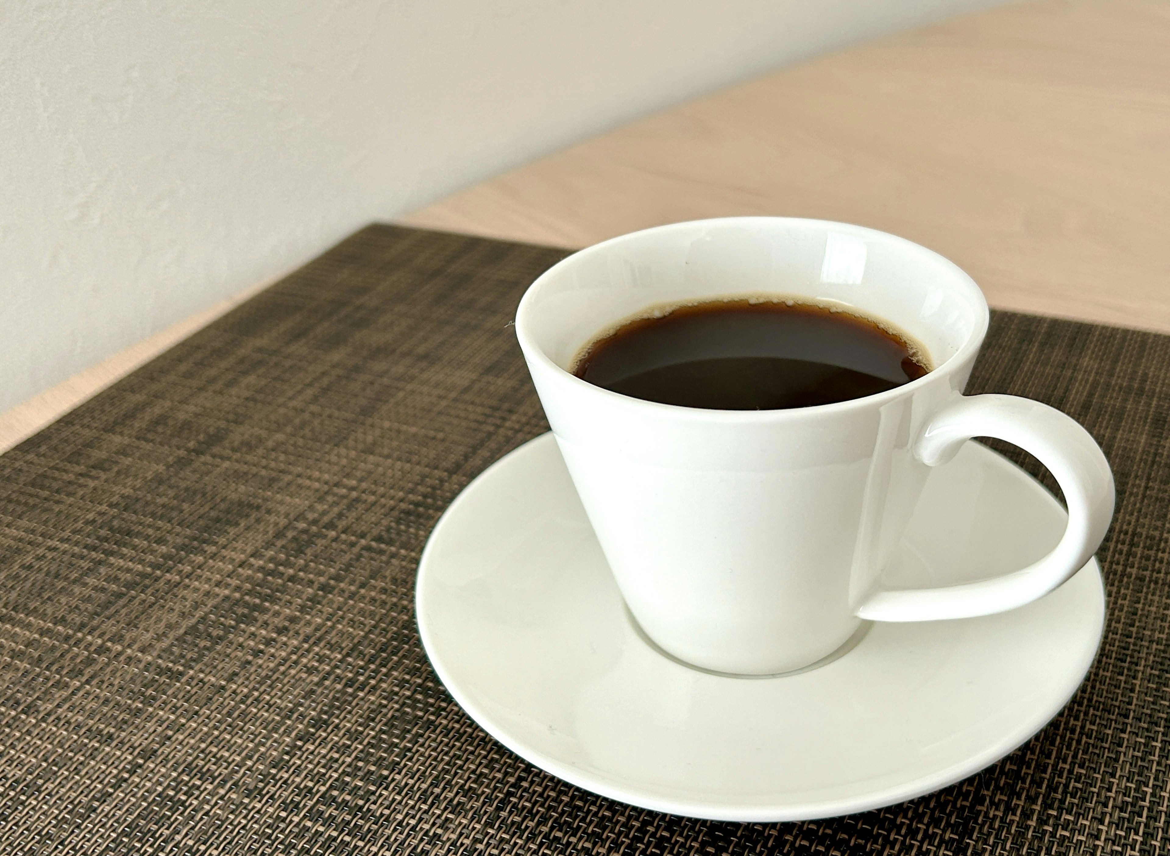 Una taza blanca de café en un platillo sobre una mesa