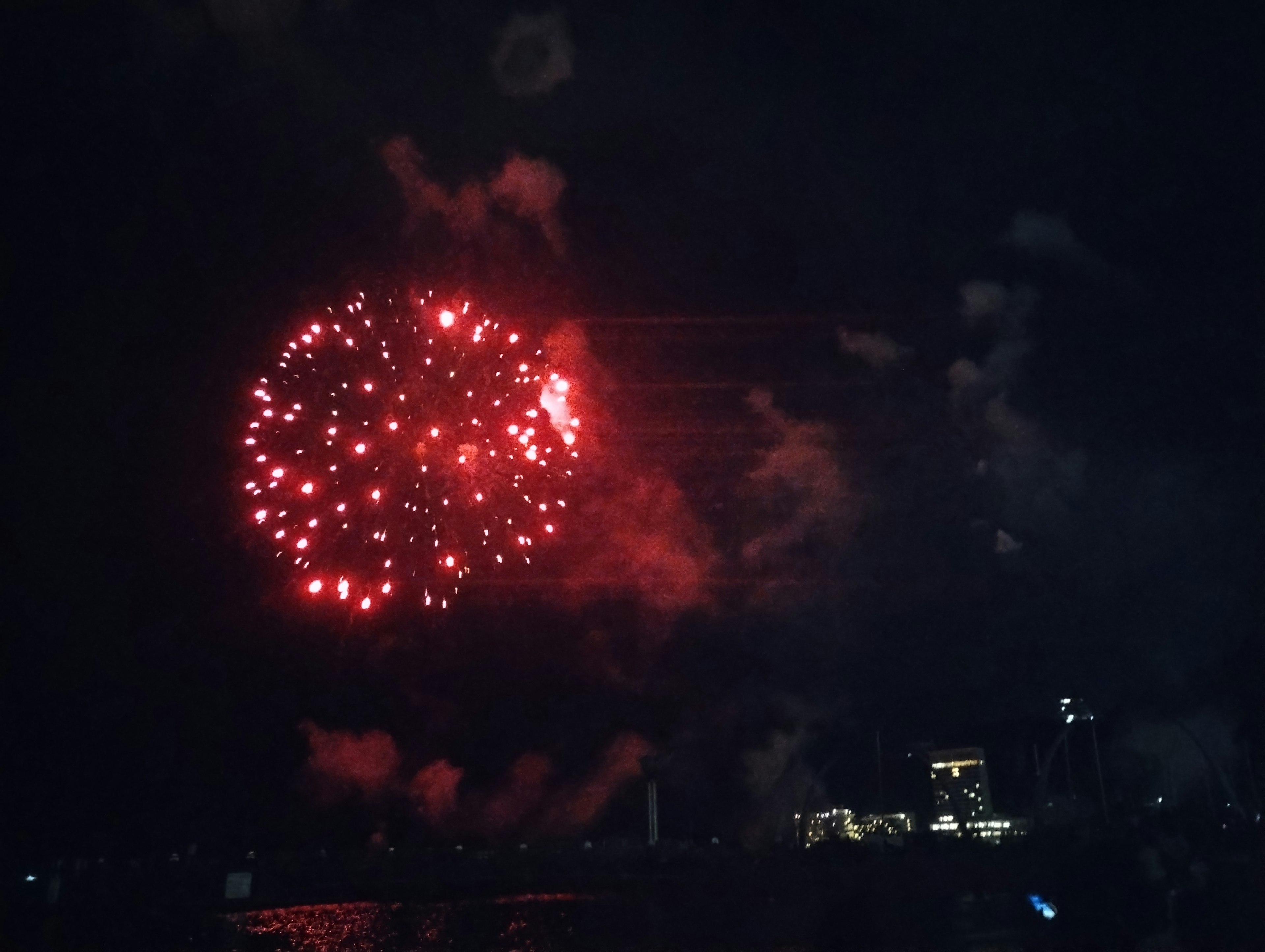 Fuegos artificiales rojos estallando en el cielo nocturno con humo