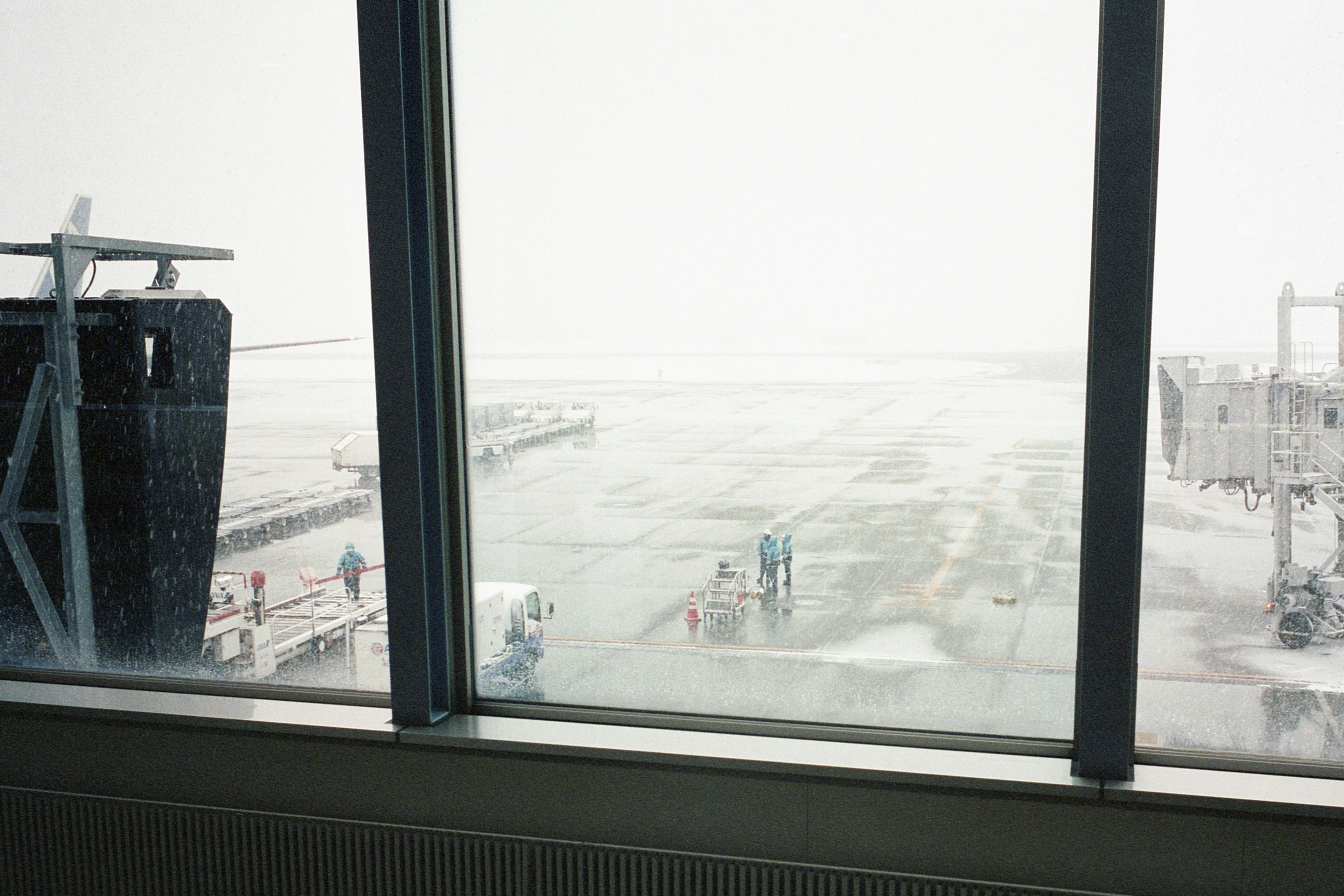 Vista de un aeropuerto nevado con personas y pista a través de una ventana