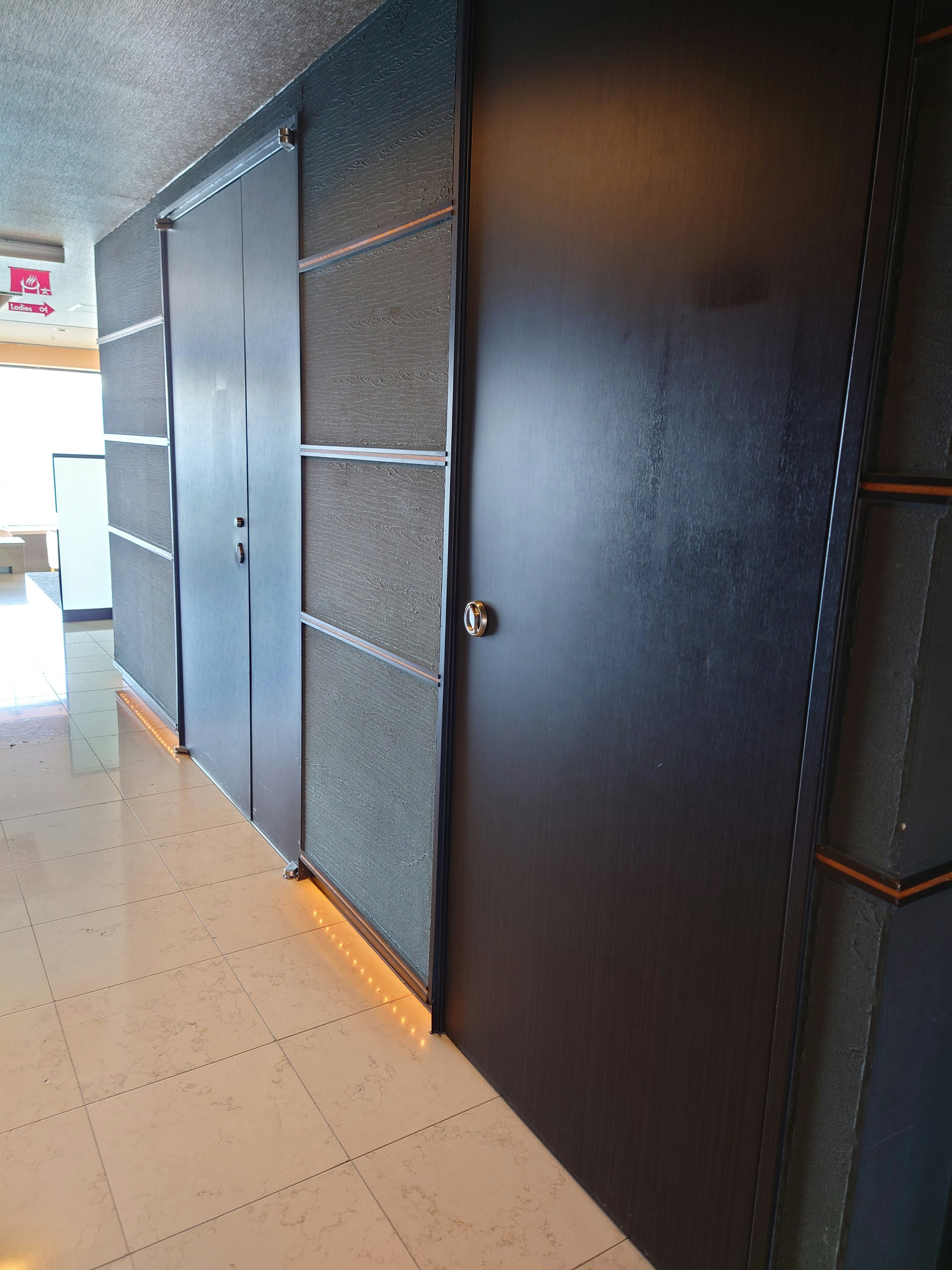 Koridor modern dengan pintu hitam dan desain pintu geser