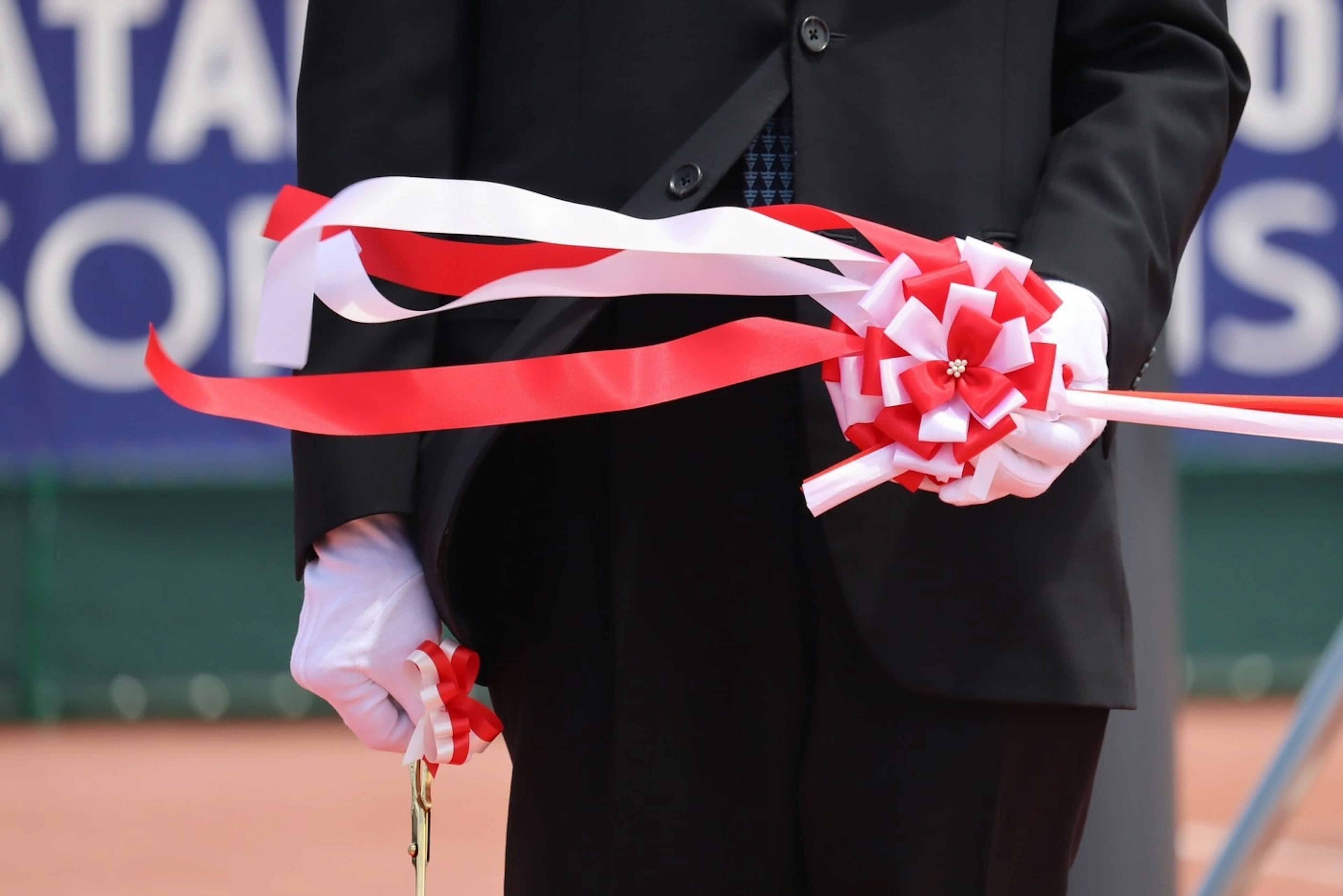 Man in a suit holding red and white ribbon with a bow