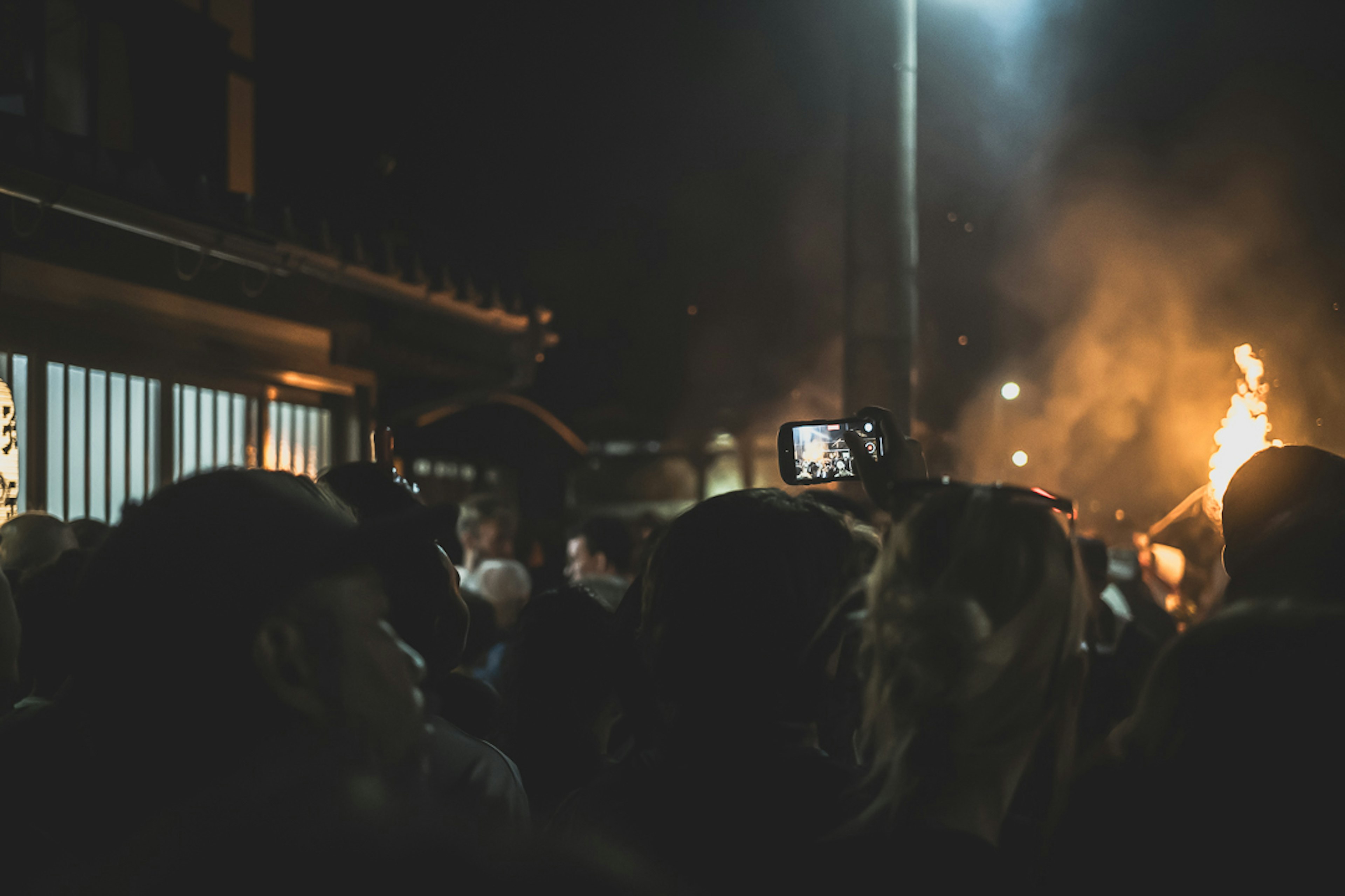 Kerumunan menikmati festival malam dengan api di latar belakang