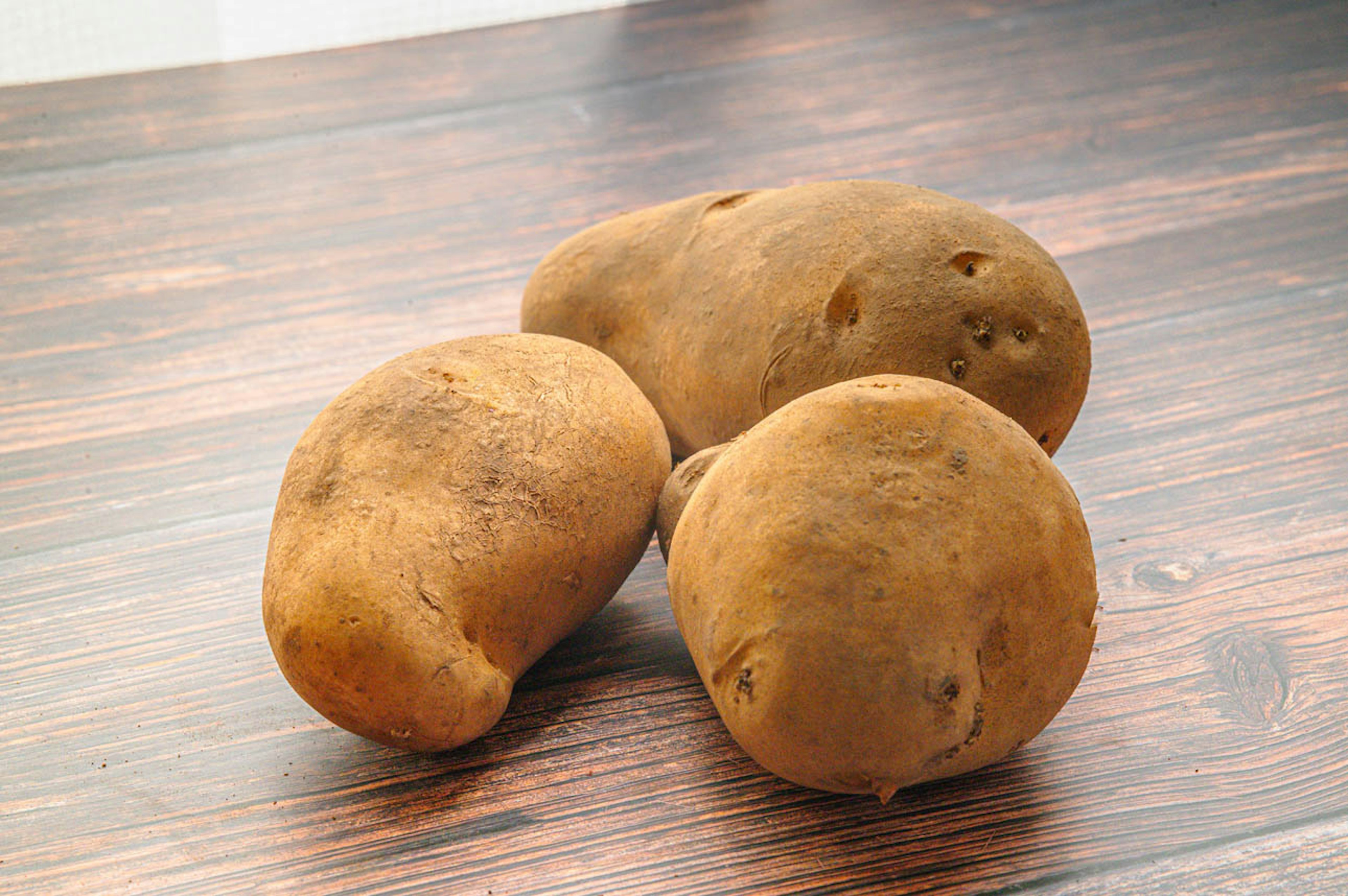 Tres patatas sobre una mesa de madera