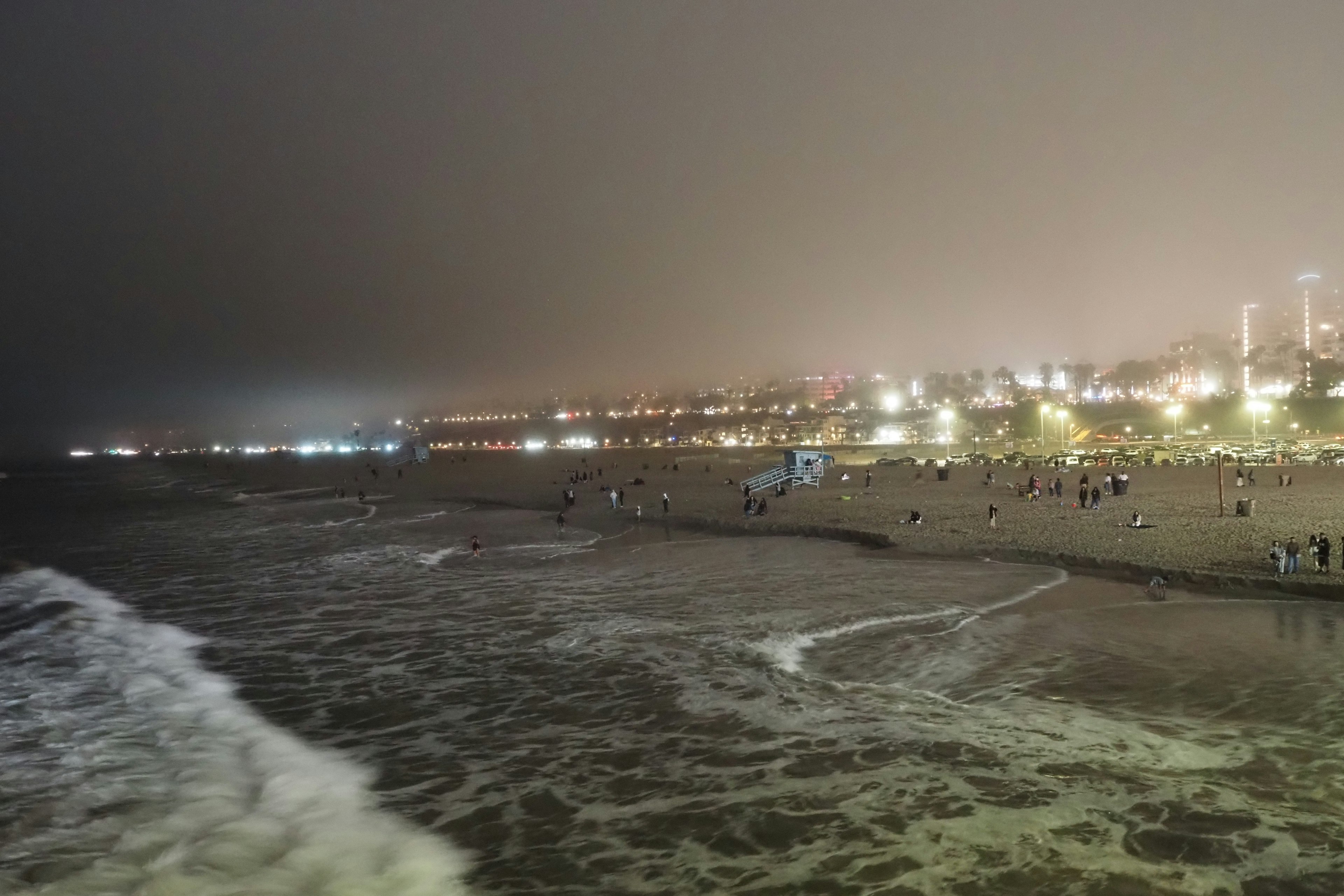 Night beach scene with waves people enjoying the shore