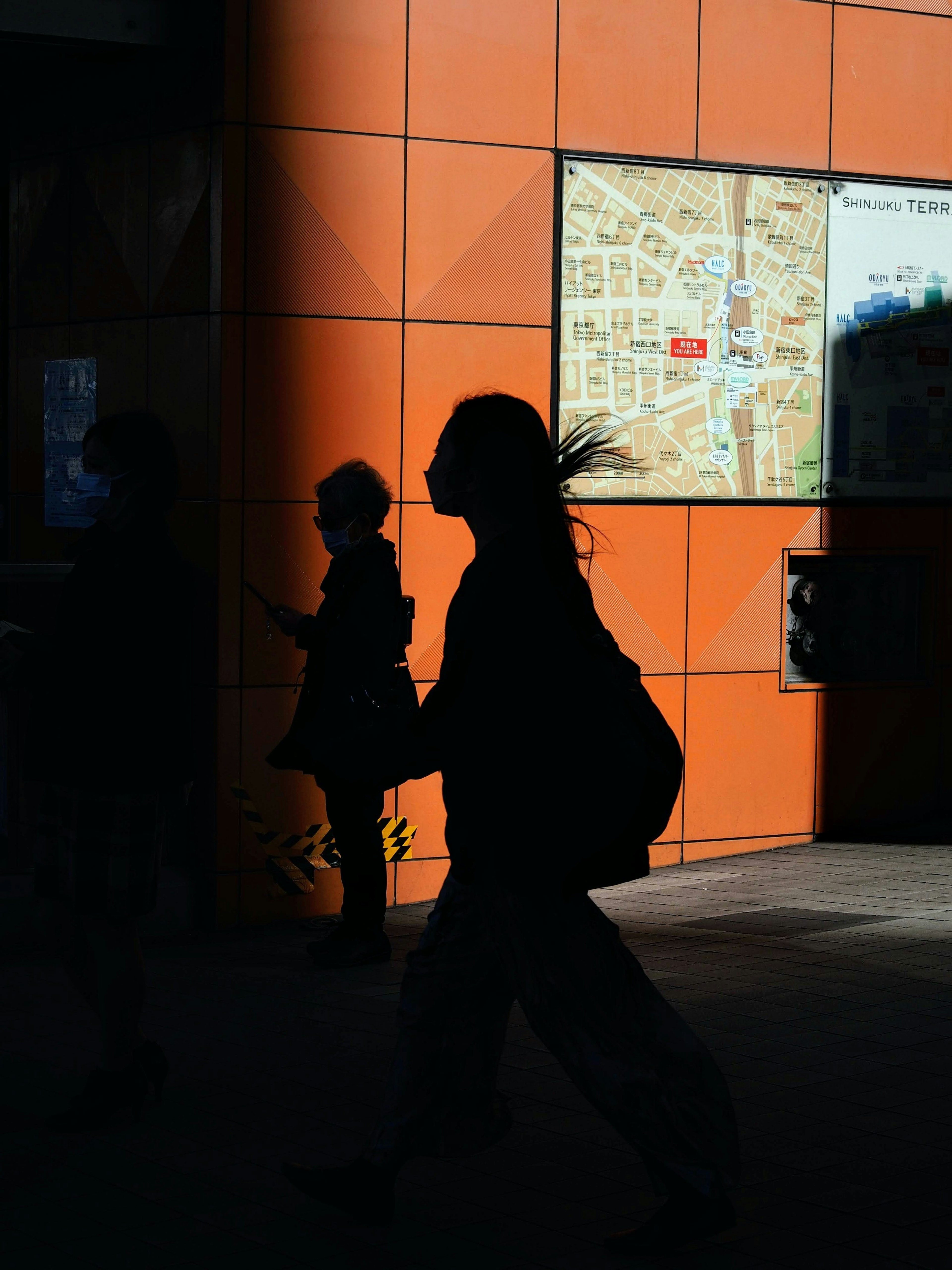 Silhouette einer Person, die vor einer orangefarbenen Wand geht