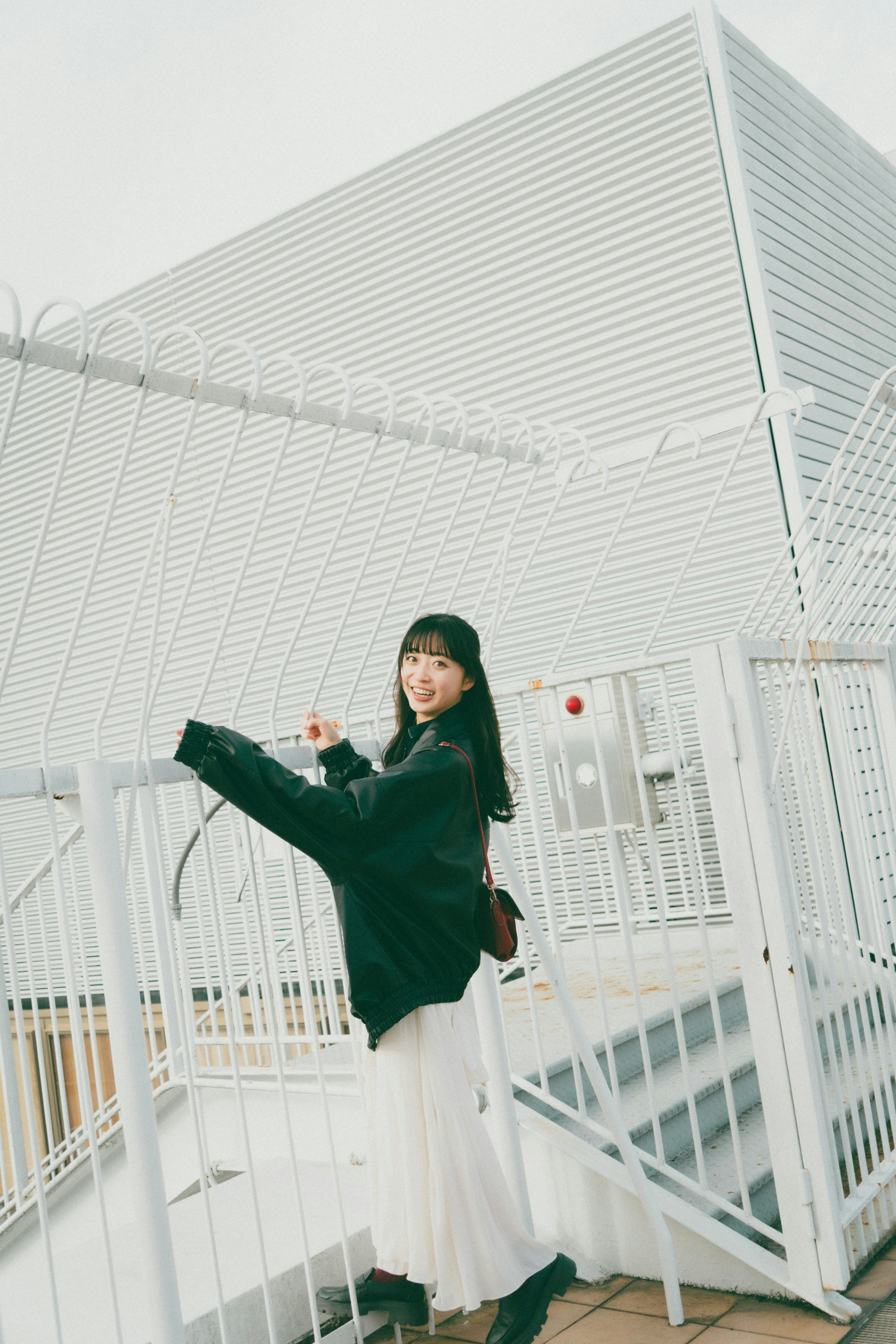 Photo de mode d'une femme posant devant une clôture blanche