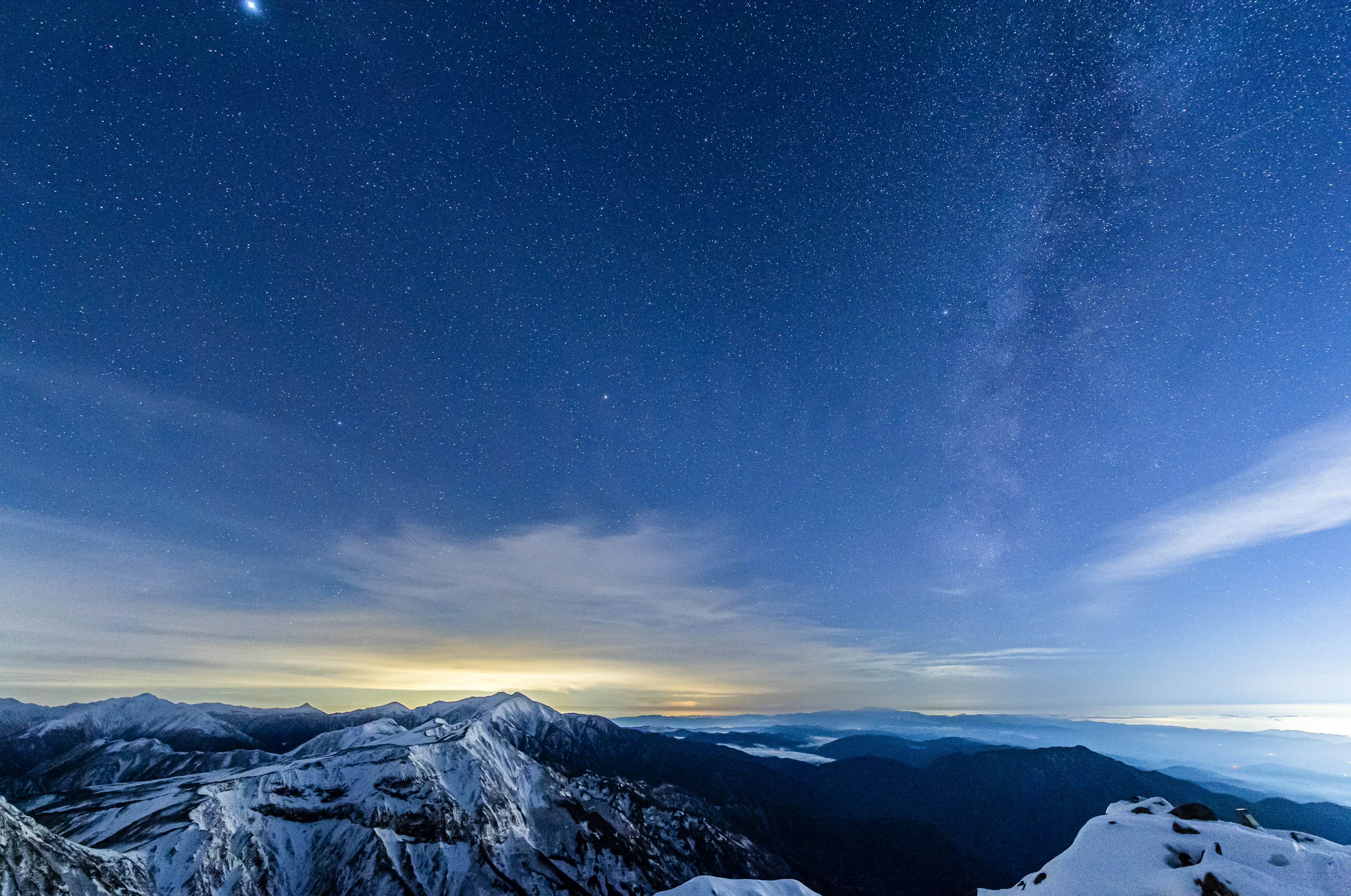 Panoramic night view of snow-covered mountains and a starry sky