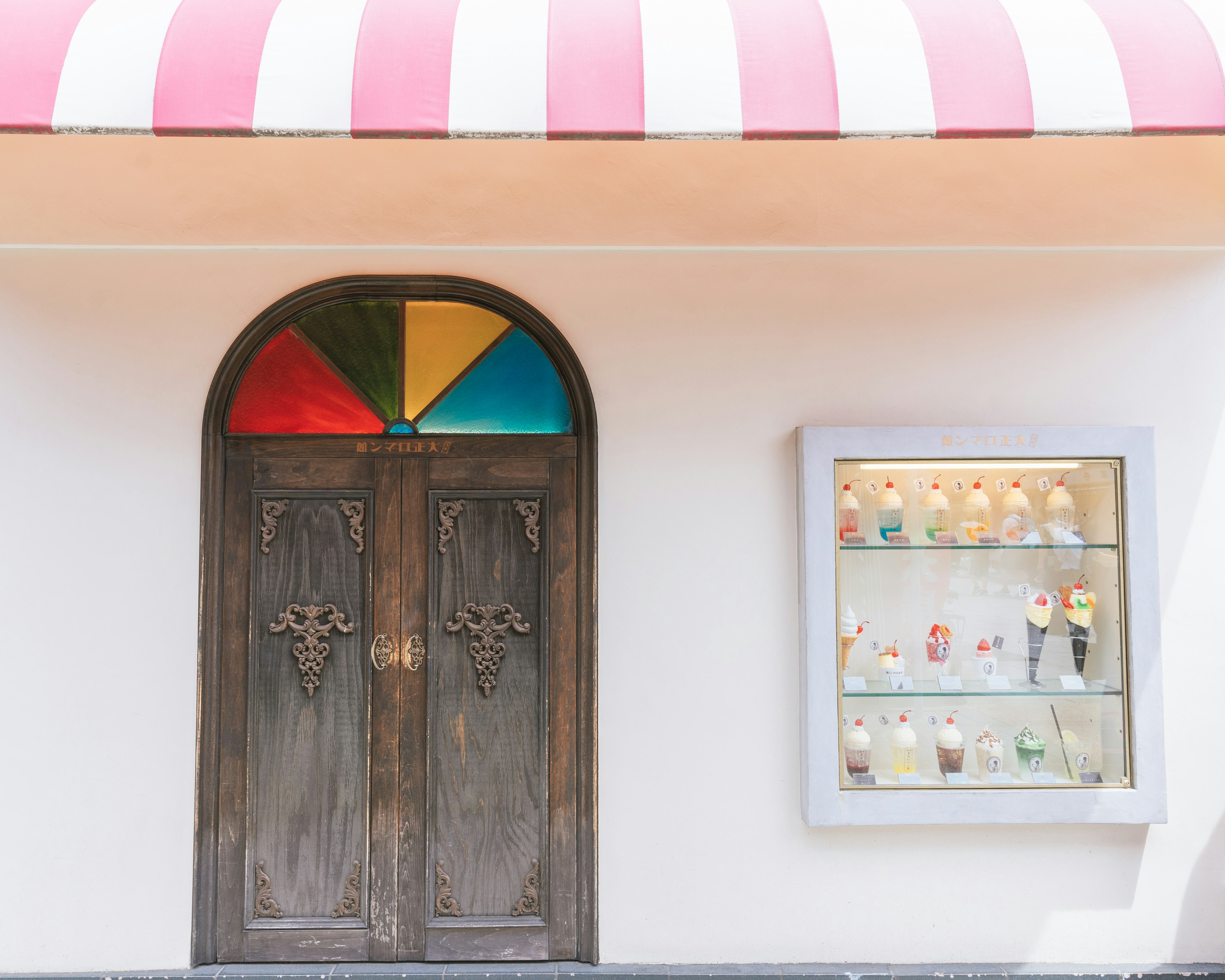 Puerta de madera con ventana de vidrio colorido y vitrina de helados en el exterior