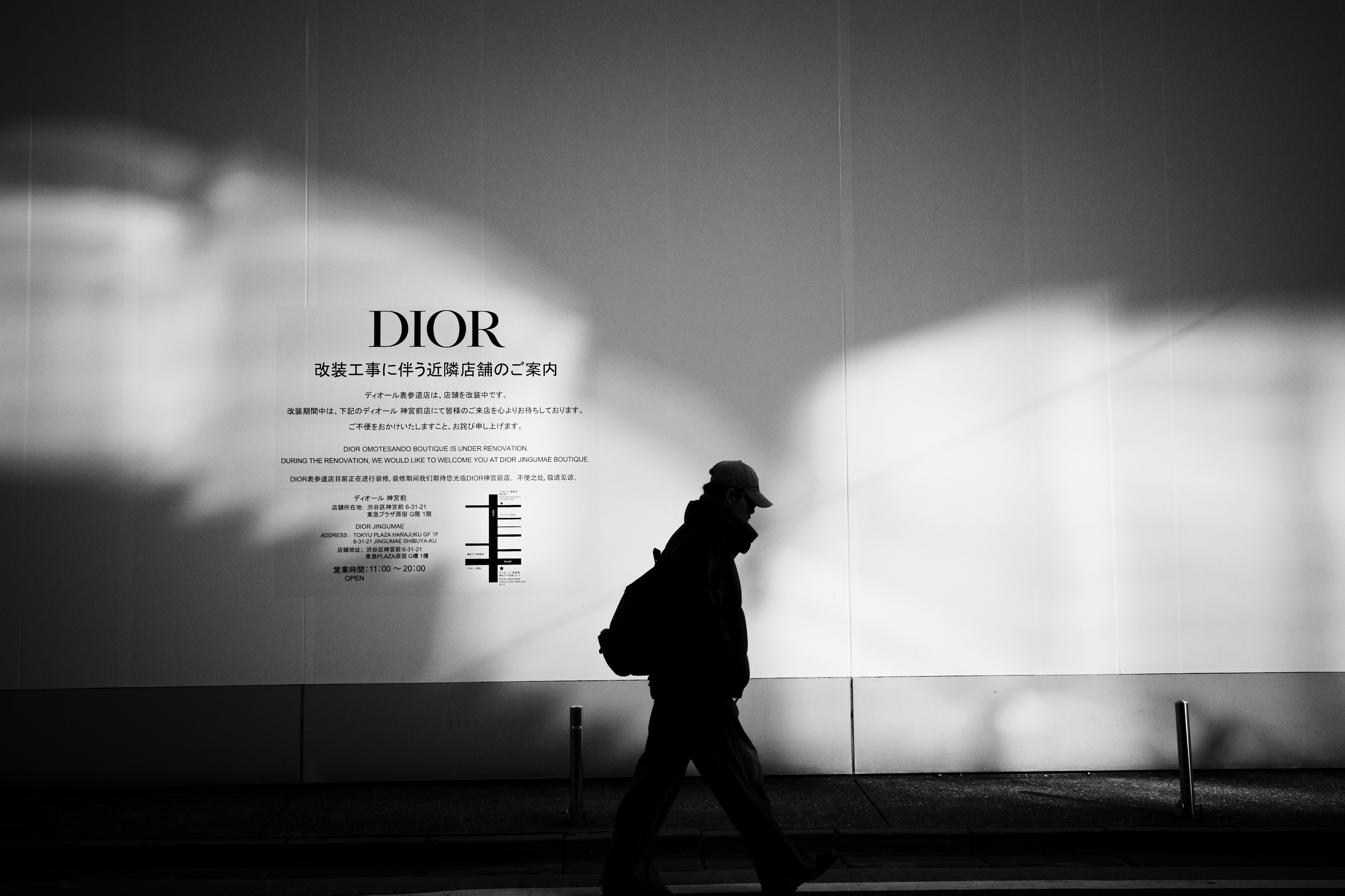 Silhouette einer Person, die vor einer Dior-Werbung mit kontrastierenden Schatten geht