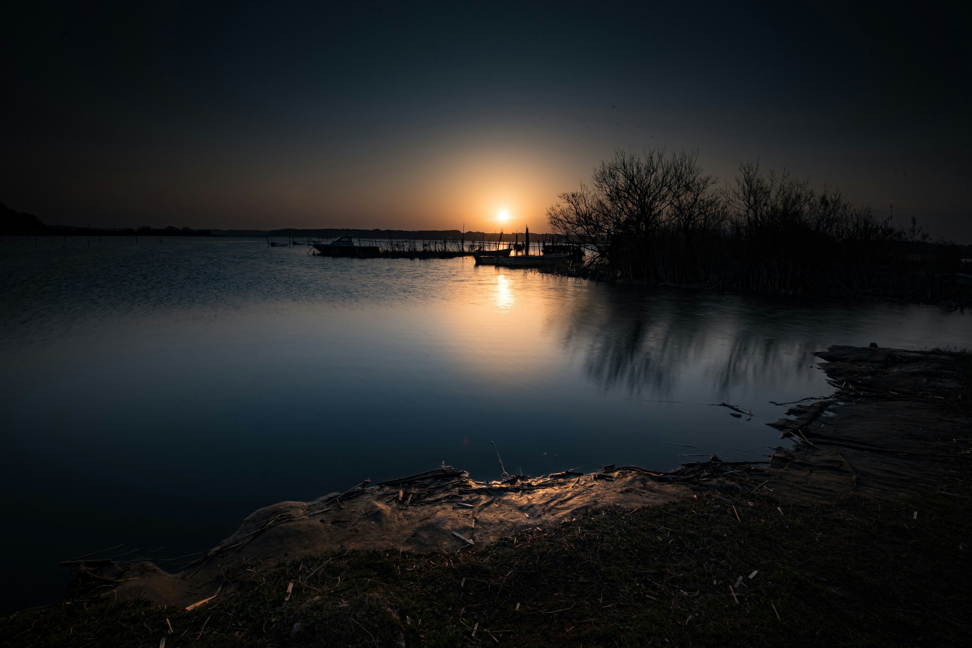 Lago tranquilo al atardecer con reflejos y siluetas