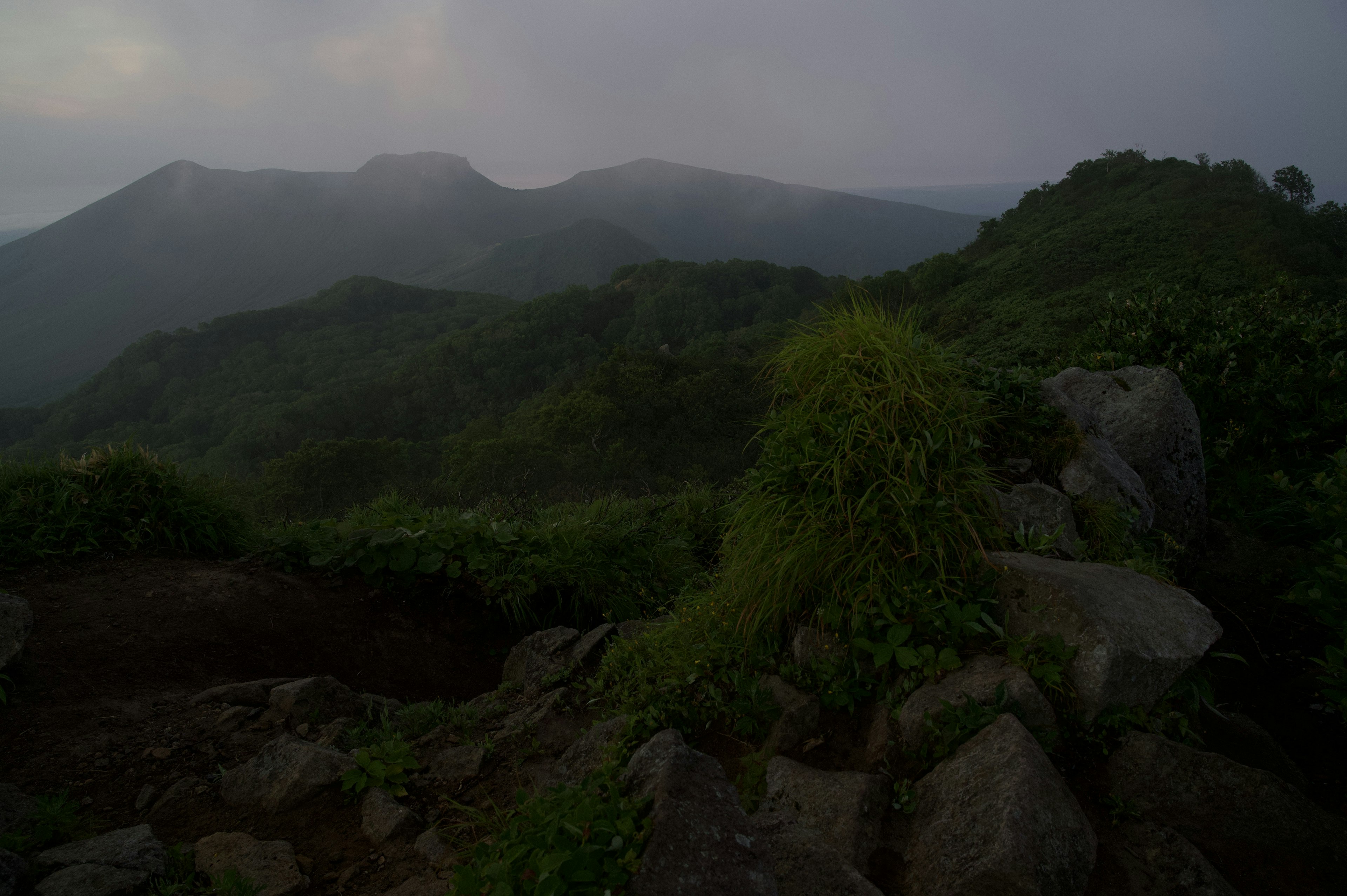 霧に包まれた山々と緑豊かな丘陵の風景