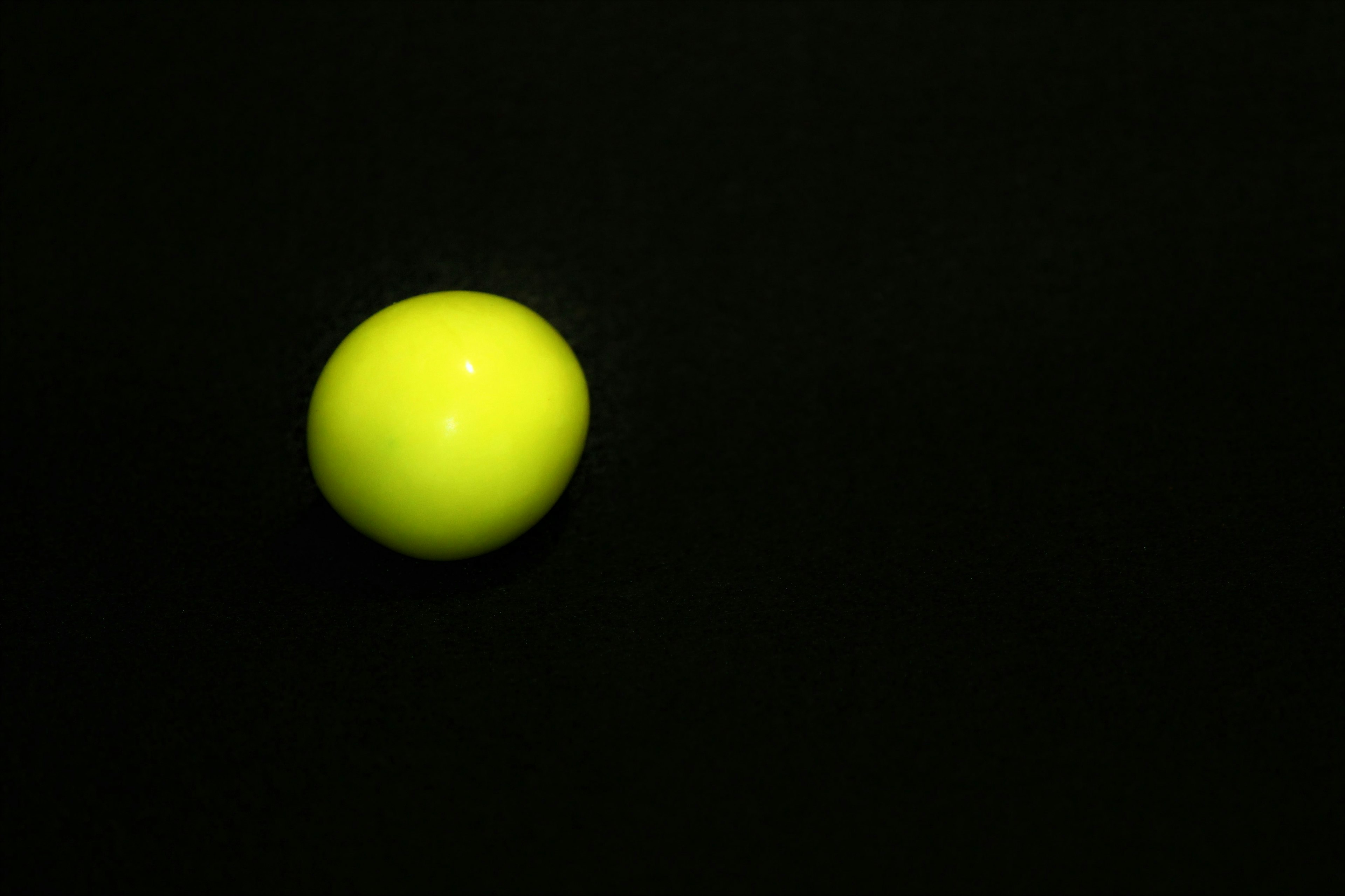 Bright yellow ball floating against a black background