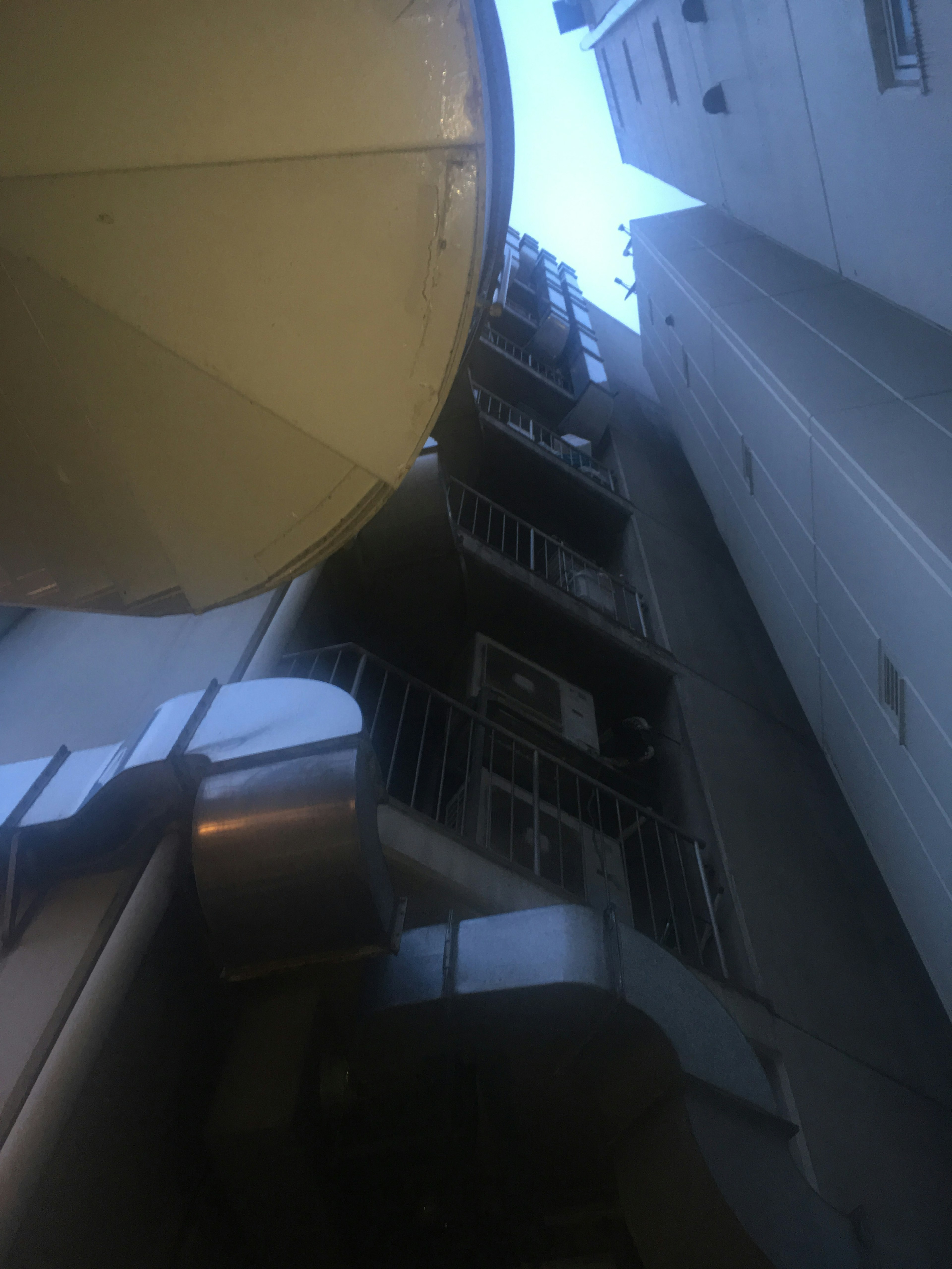 View of a narrow alley with a tall building and yellow equipment