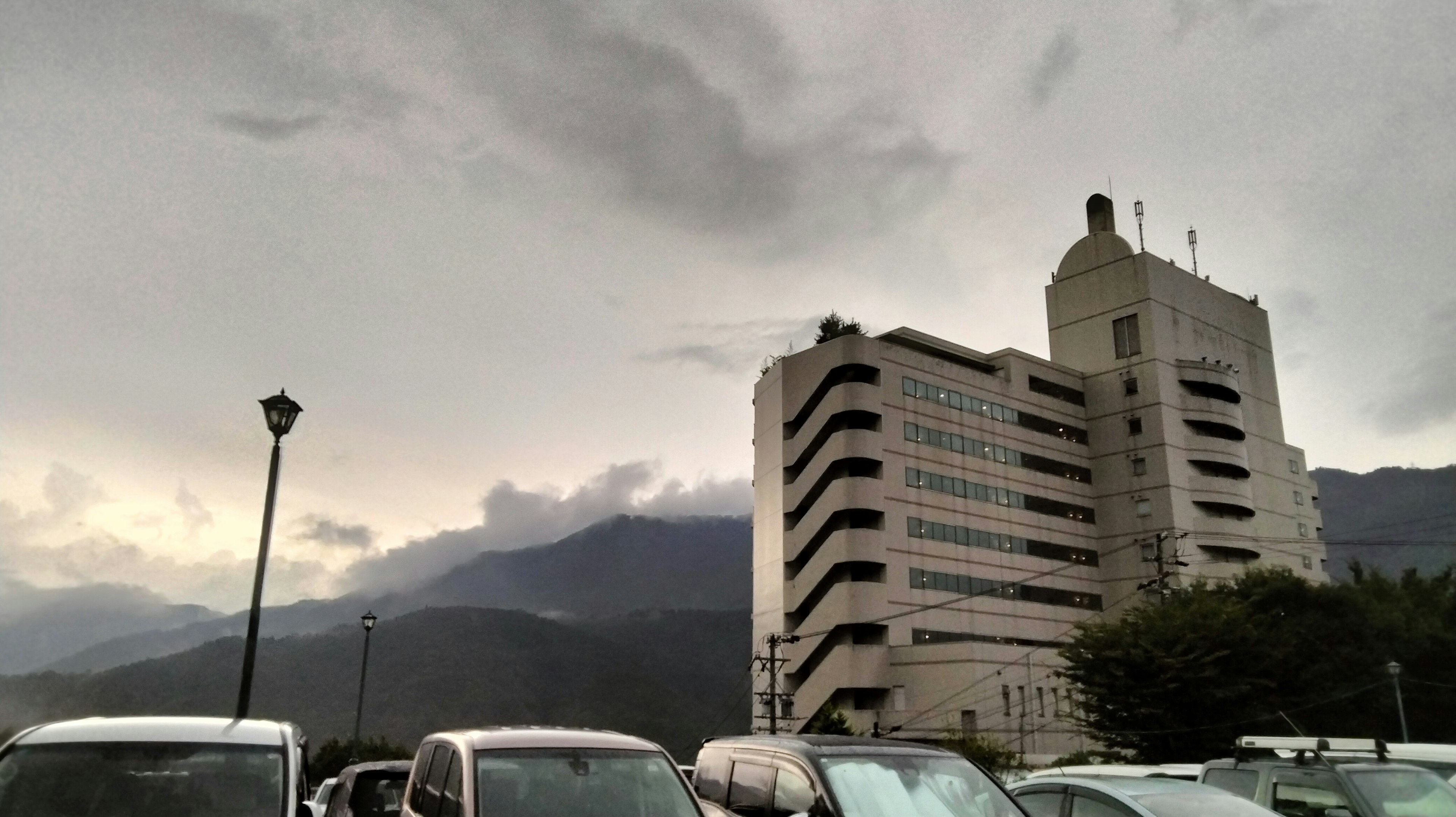 Edificio moderno bajo un cielo nublado con coches alrededor