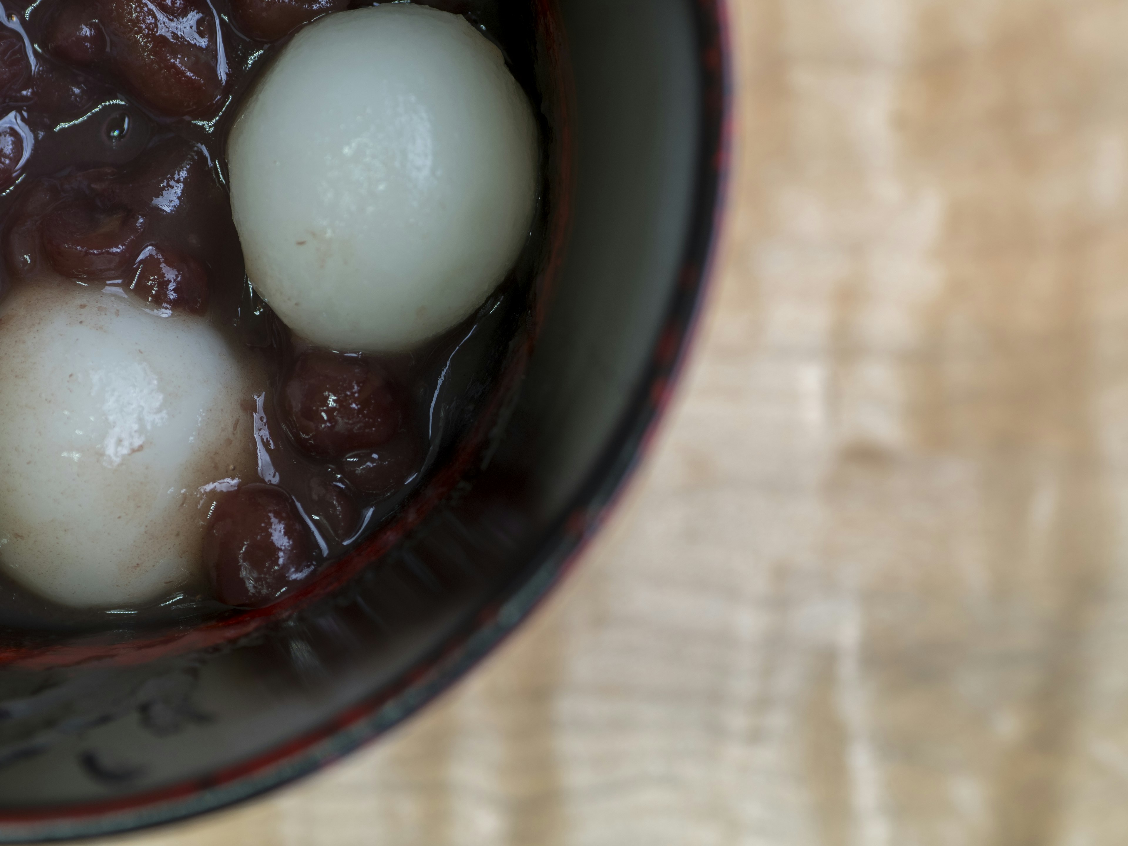 A bowl of sweet red bean soup with two white rice dumplings