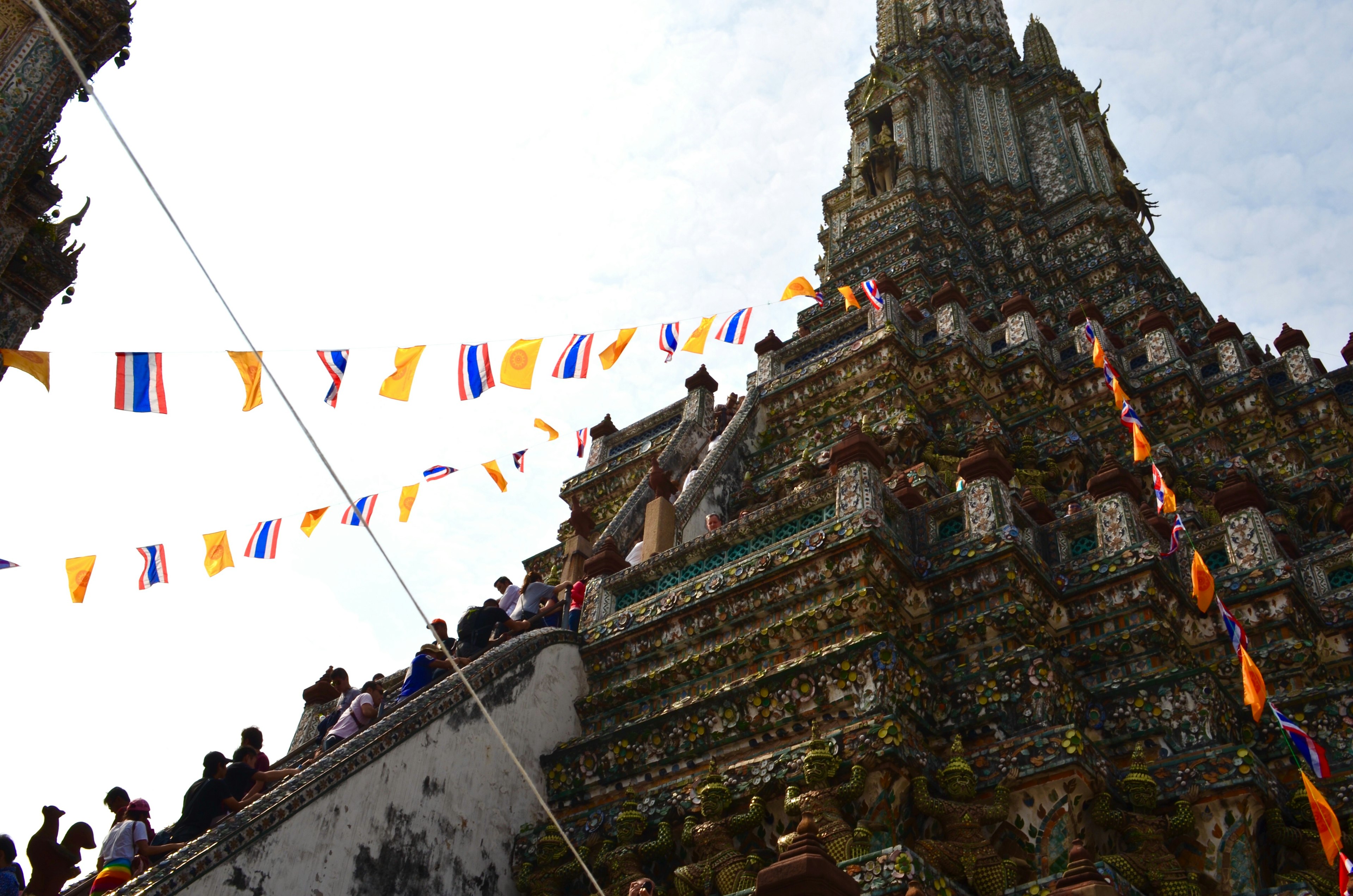 Vista del templo Wat Arun en Bangkok con banderas coloridas y arquitectura ornamentada