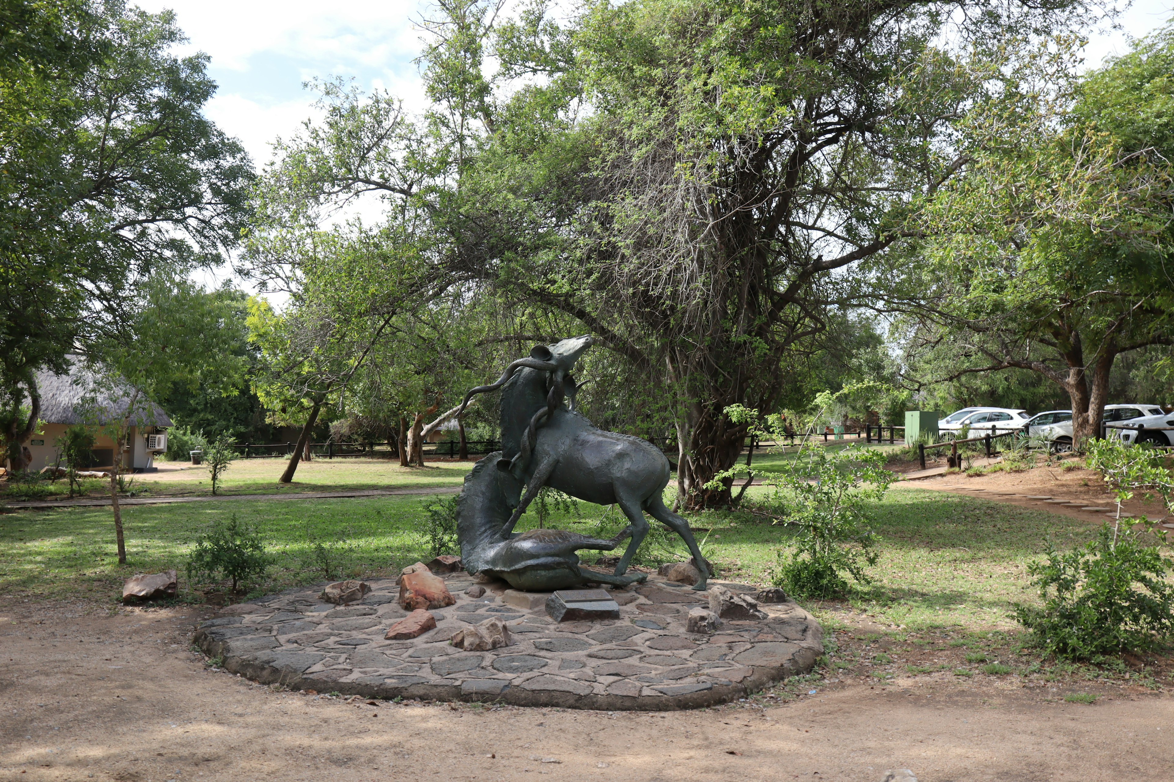 A blue sculpture of a rearing horse surrounded by lush greenery