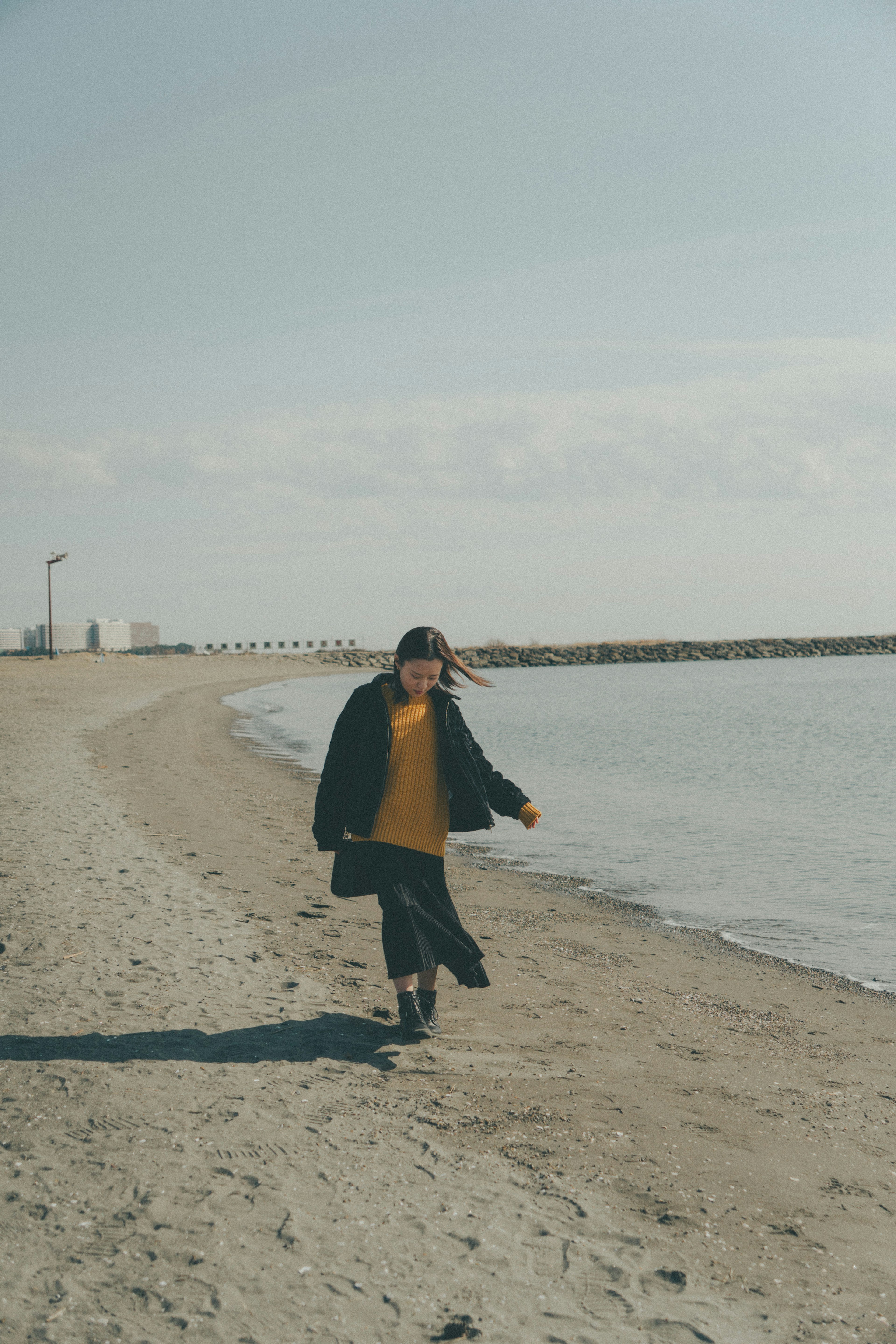 Persona caminando en una playa con agua tranquila