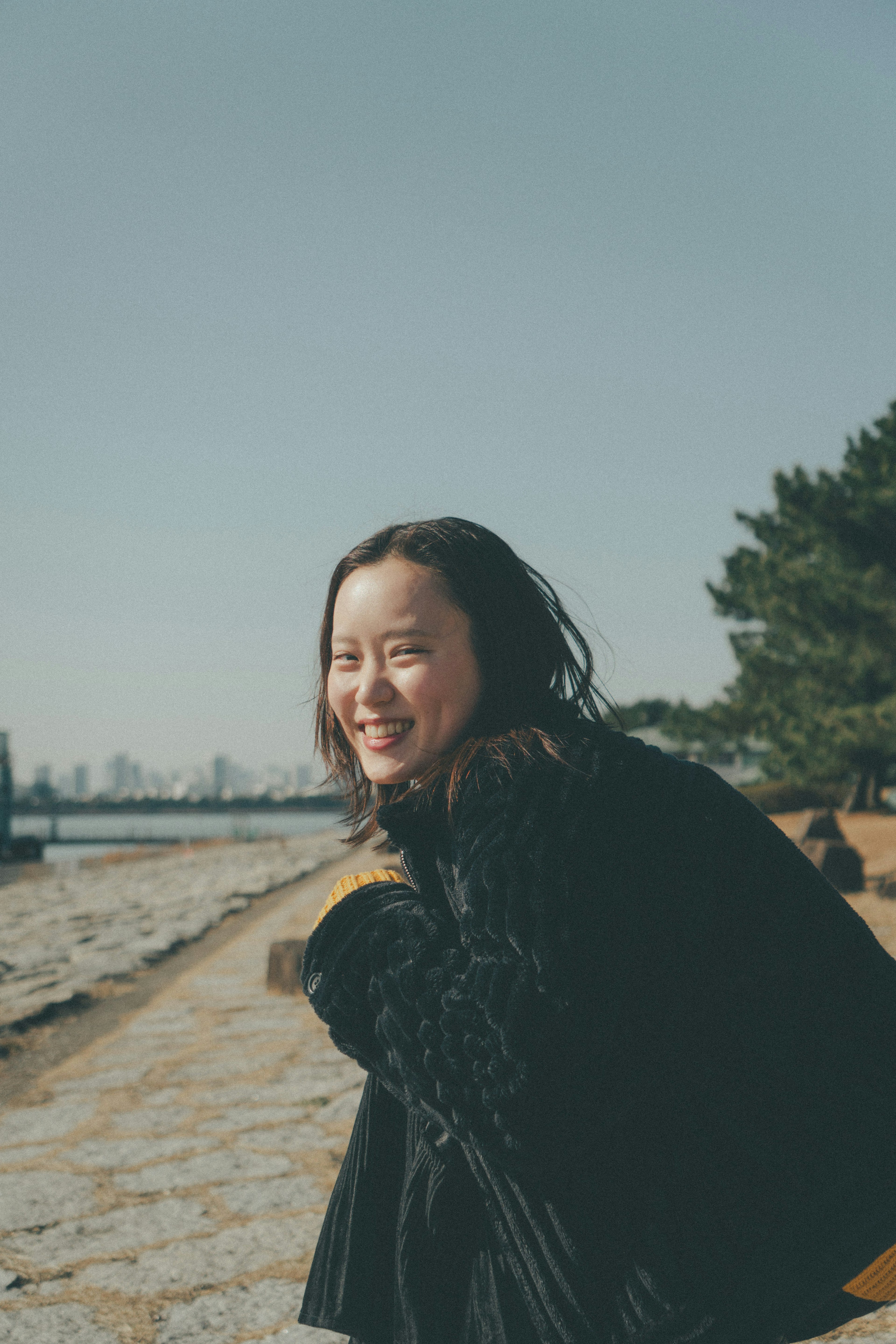 穿著黑色服裝在公園裡微笑的女性