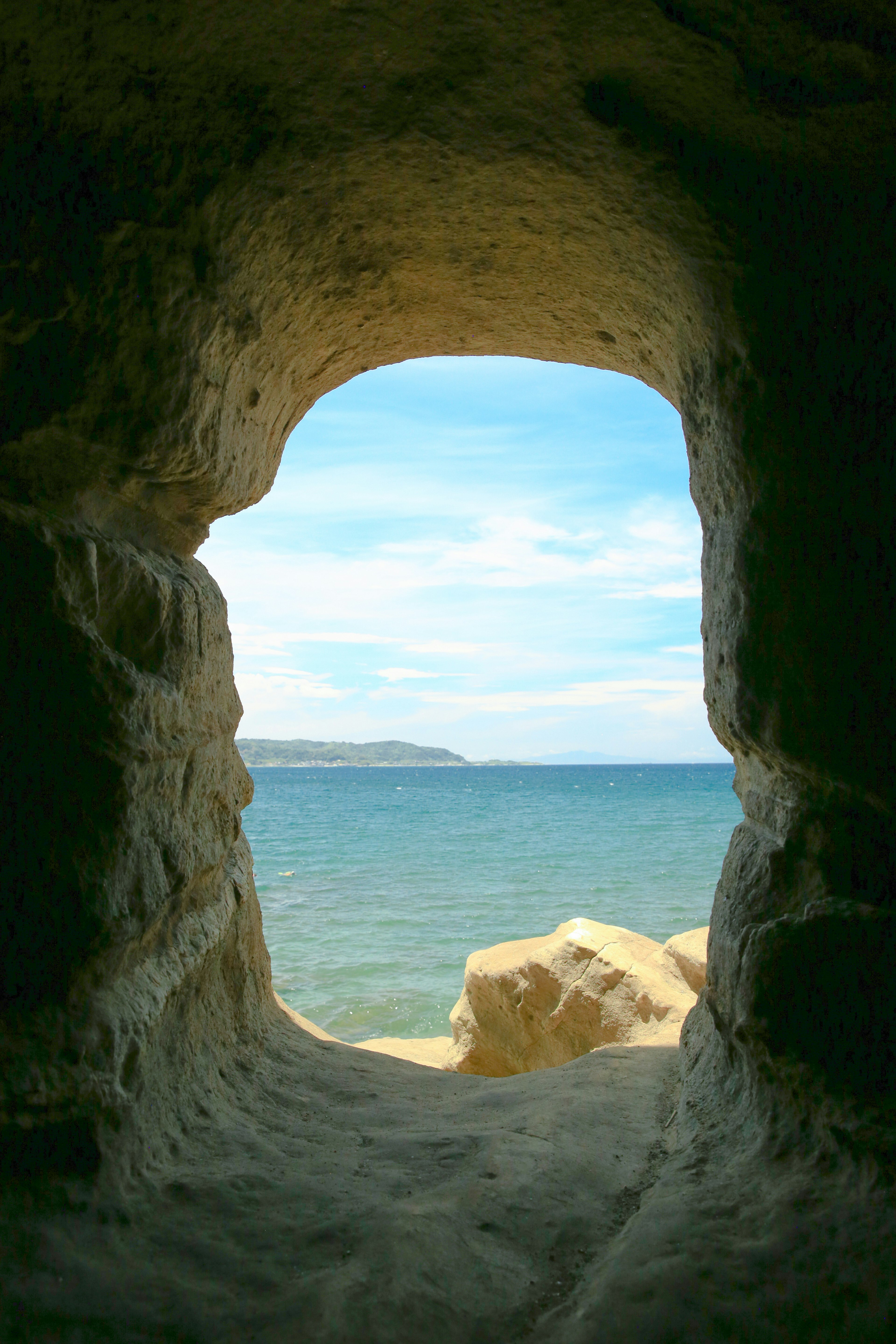 View of the sea and blue sky through a cave opening