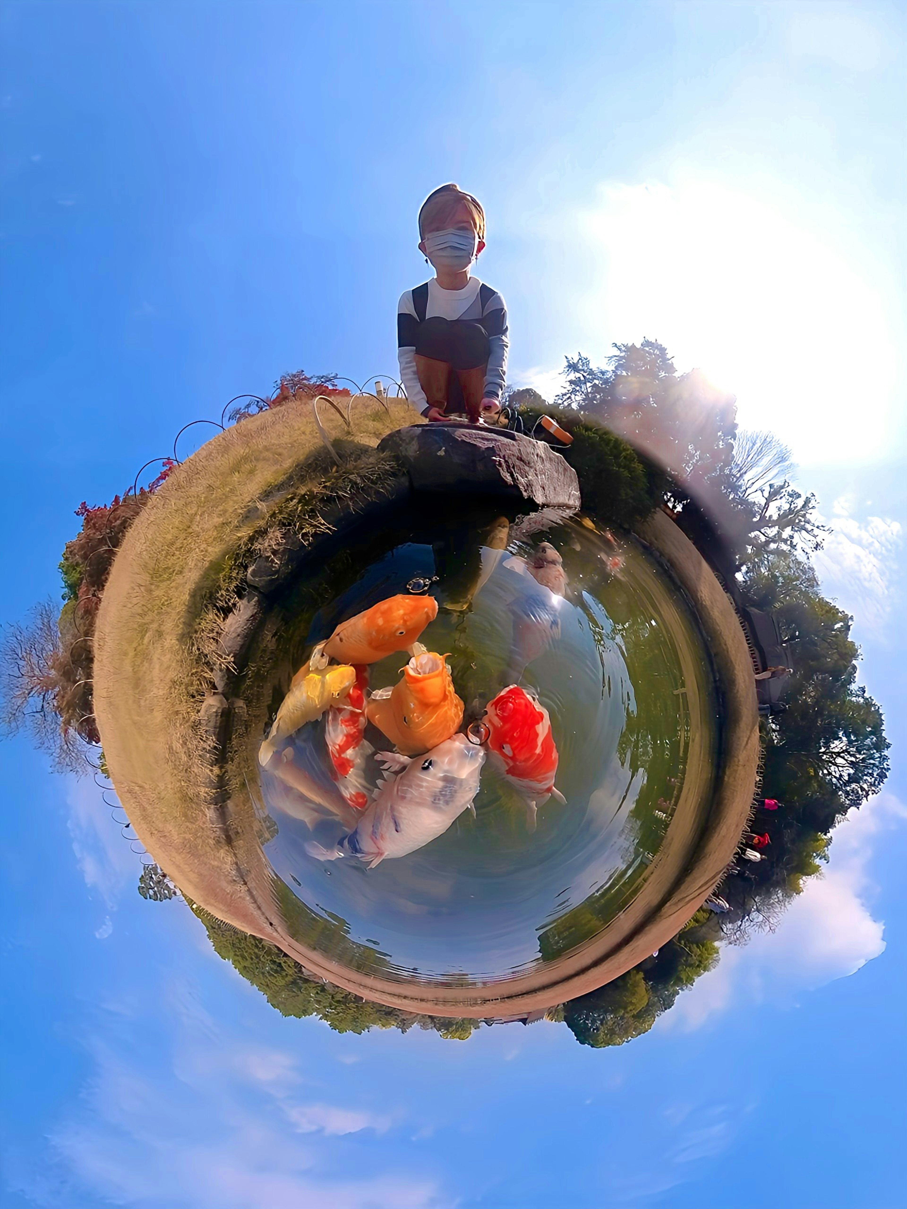 Un enfant debout près d'un étang avec des carpes colorées dans une vue à 360 degrés