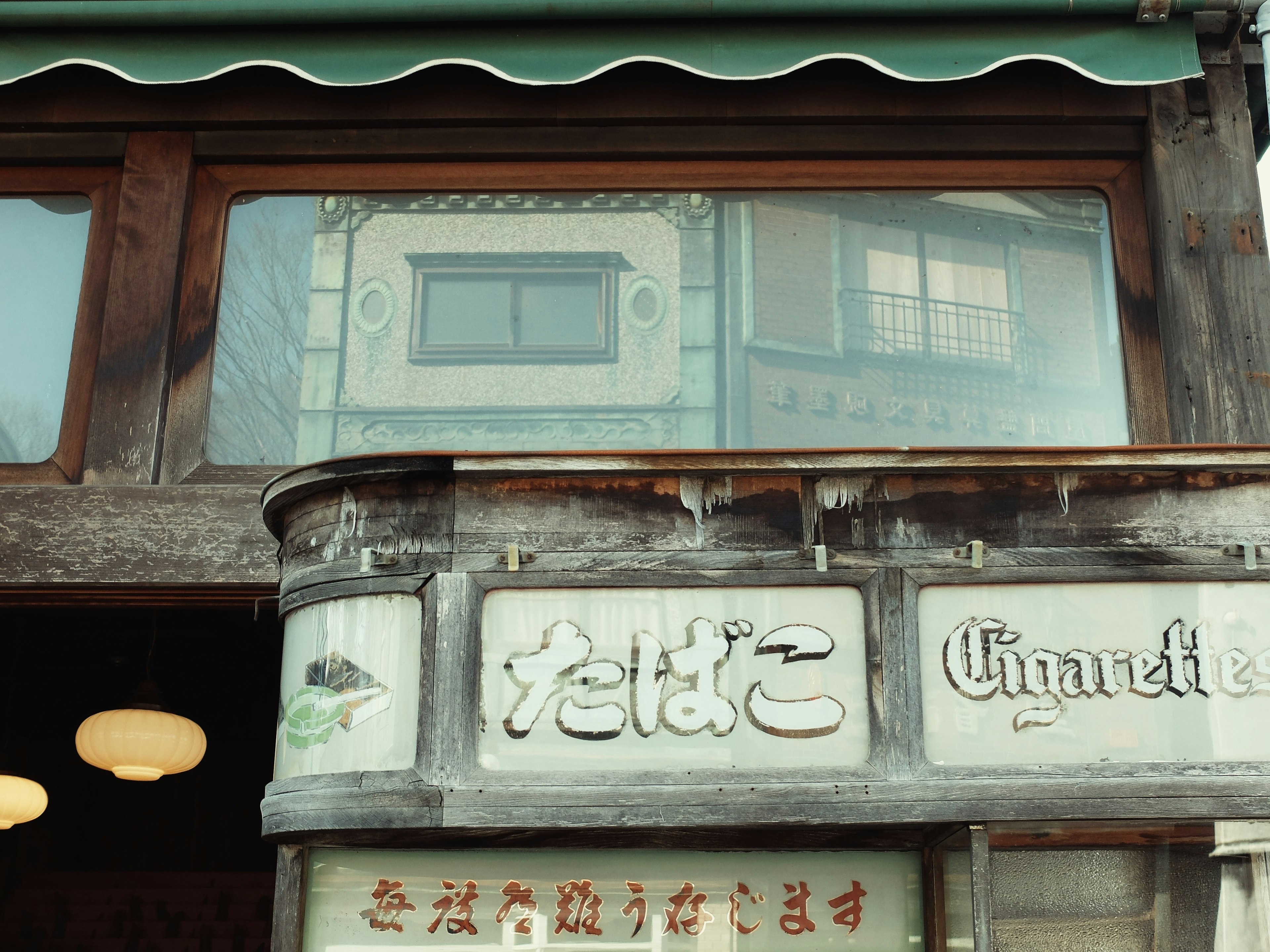 Façade de magasin japonais traditionnel avec une enseigne en bois comportant du texte japonais et français