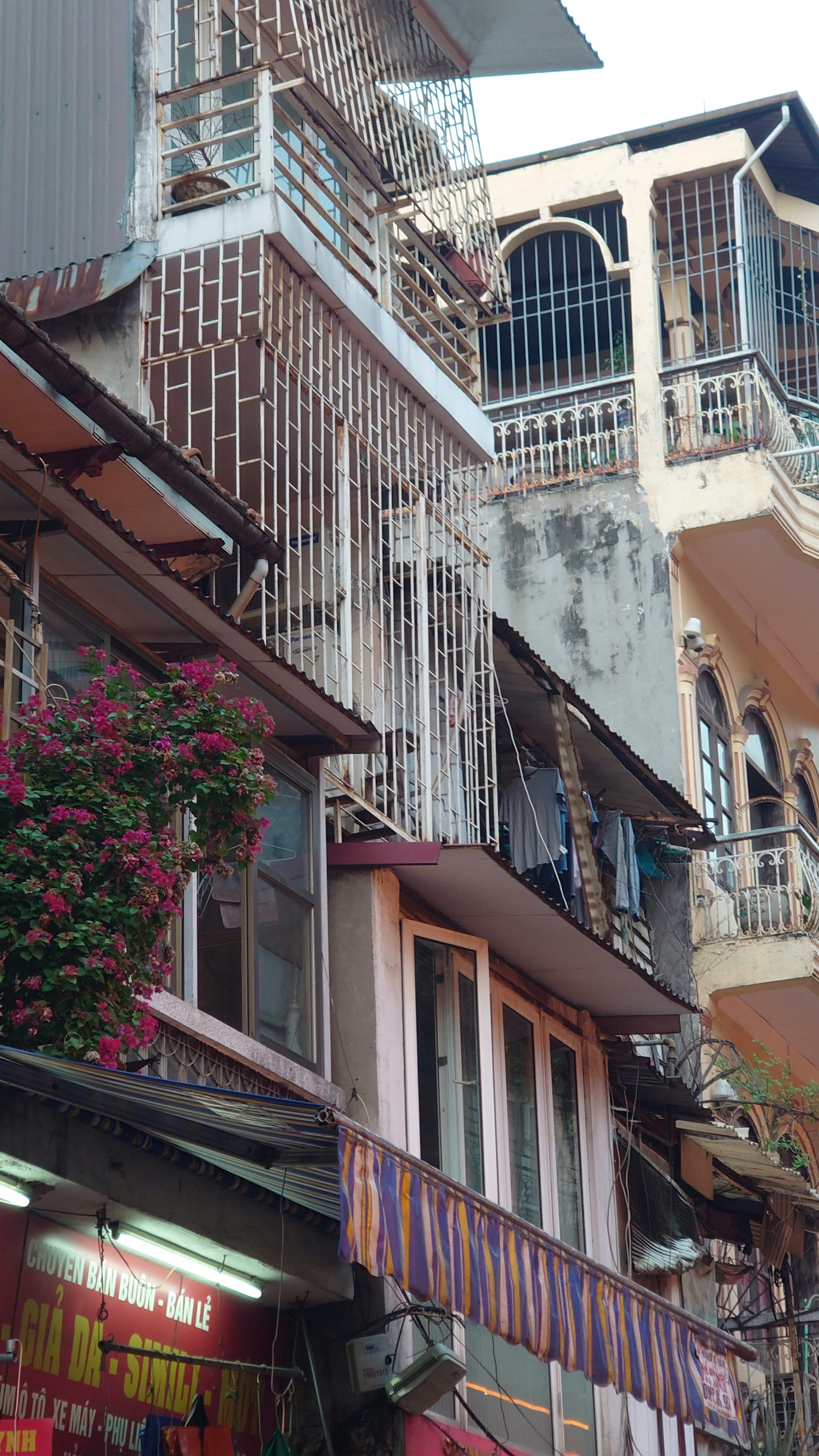 Eksterior bangunan tua dengan balkon dan pot bunga di lingkungan jalan