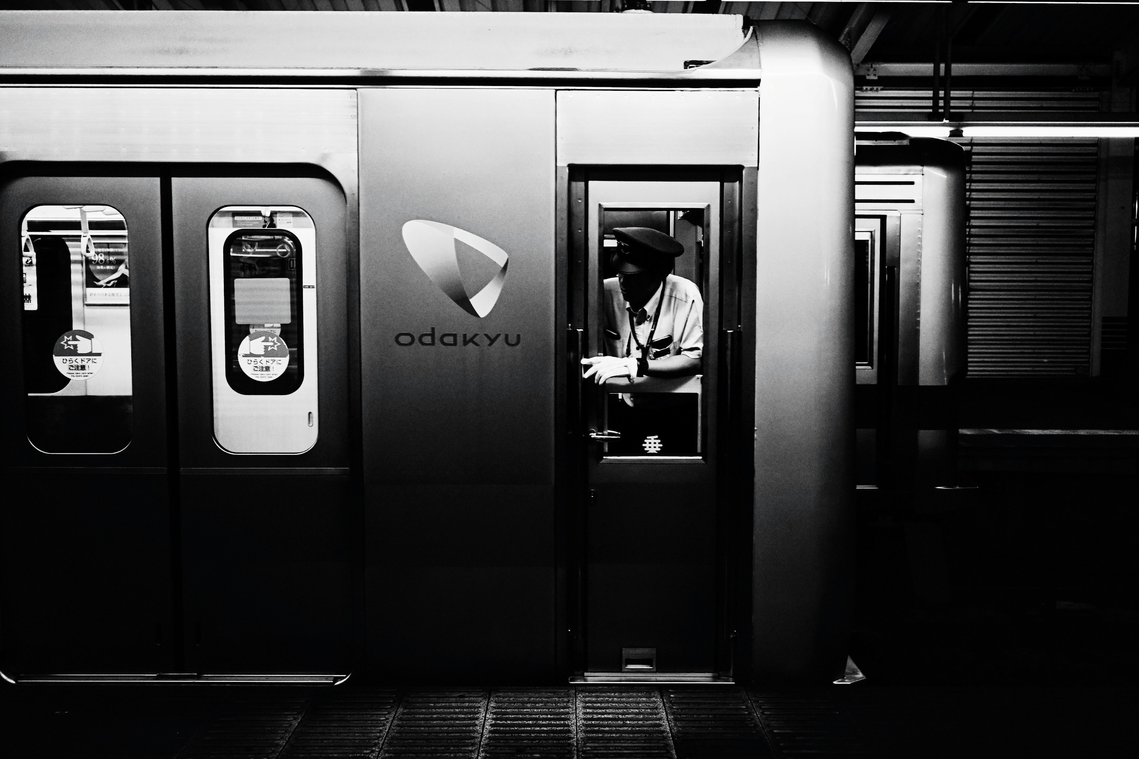 Image en noir et blanc d'une porte de train de métro ouverte avec un conducteur à l'intérieur