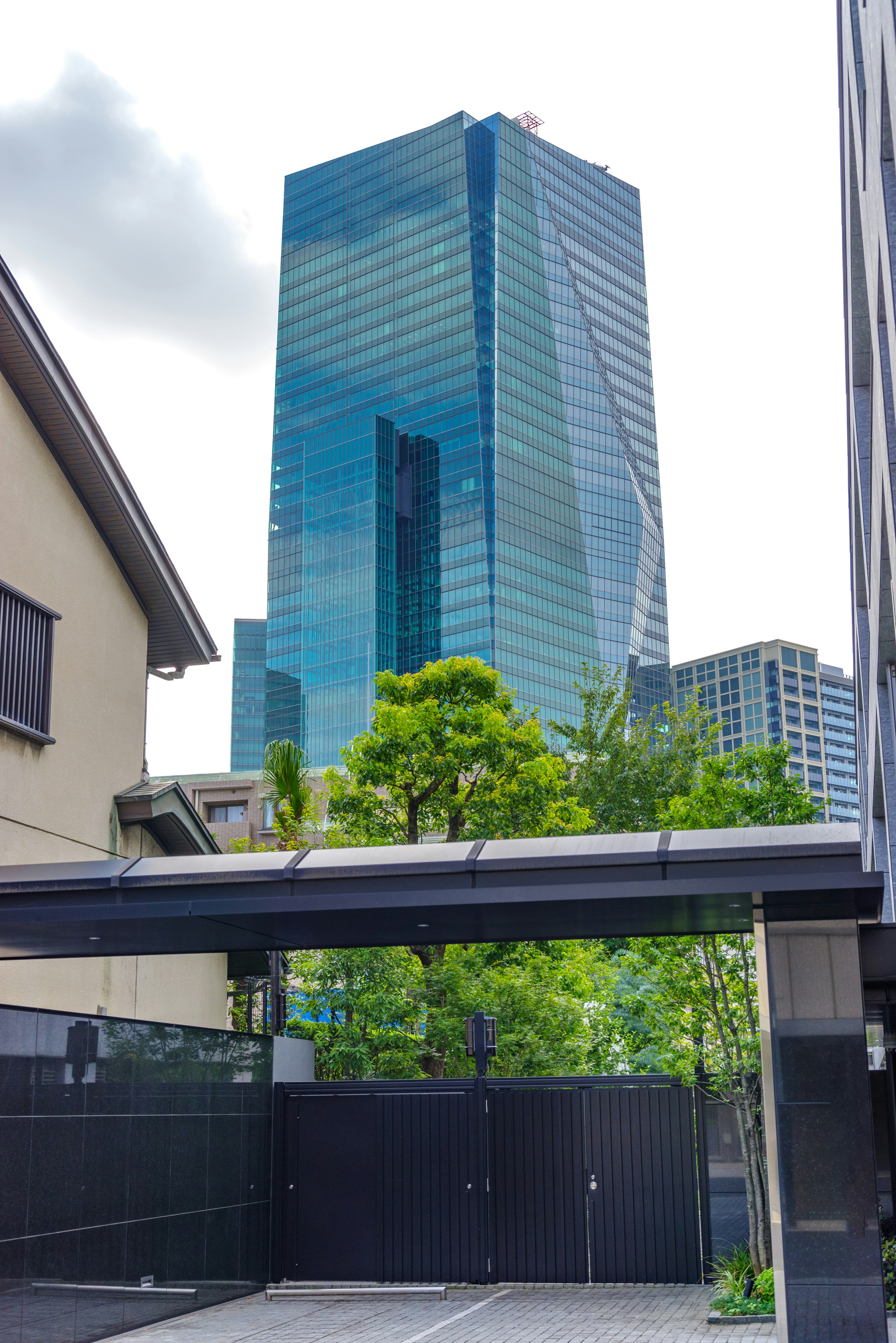 Urban landscape featuring a tall glass building and green trees