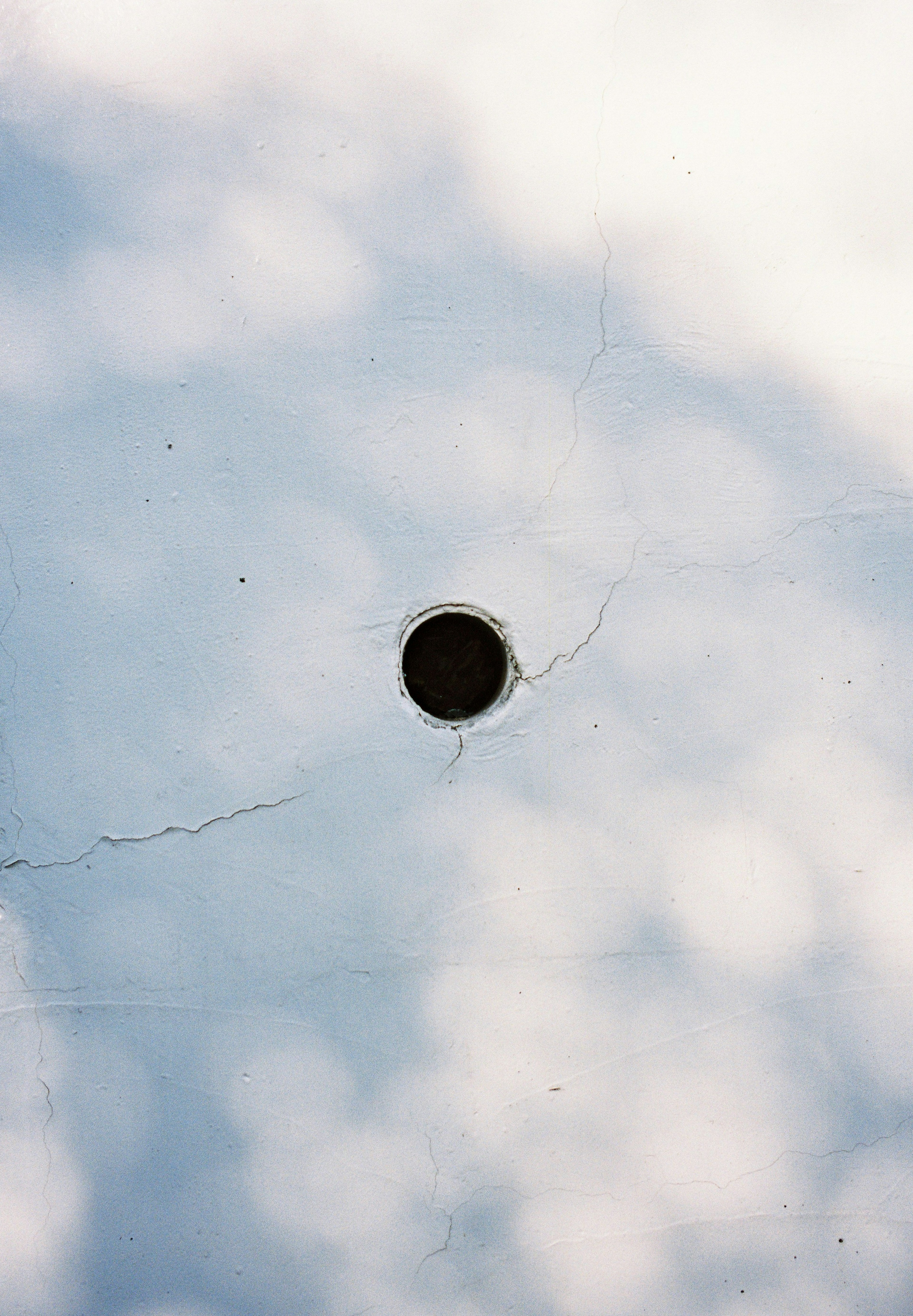 Schwarzes Loch auf einer rissigen Oberfläche unter blauem Himmel