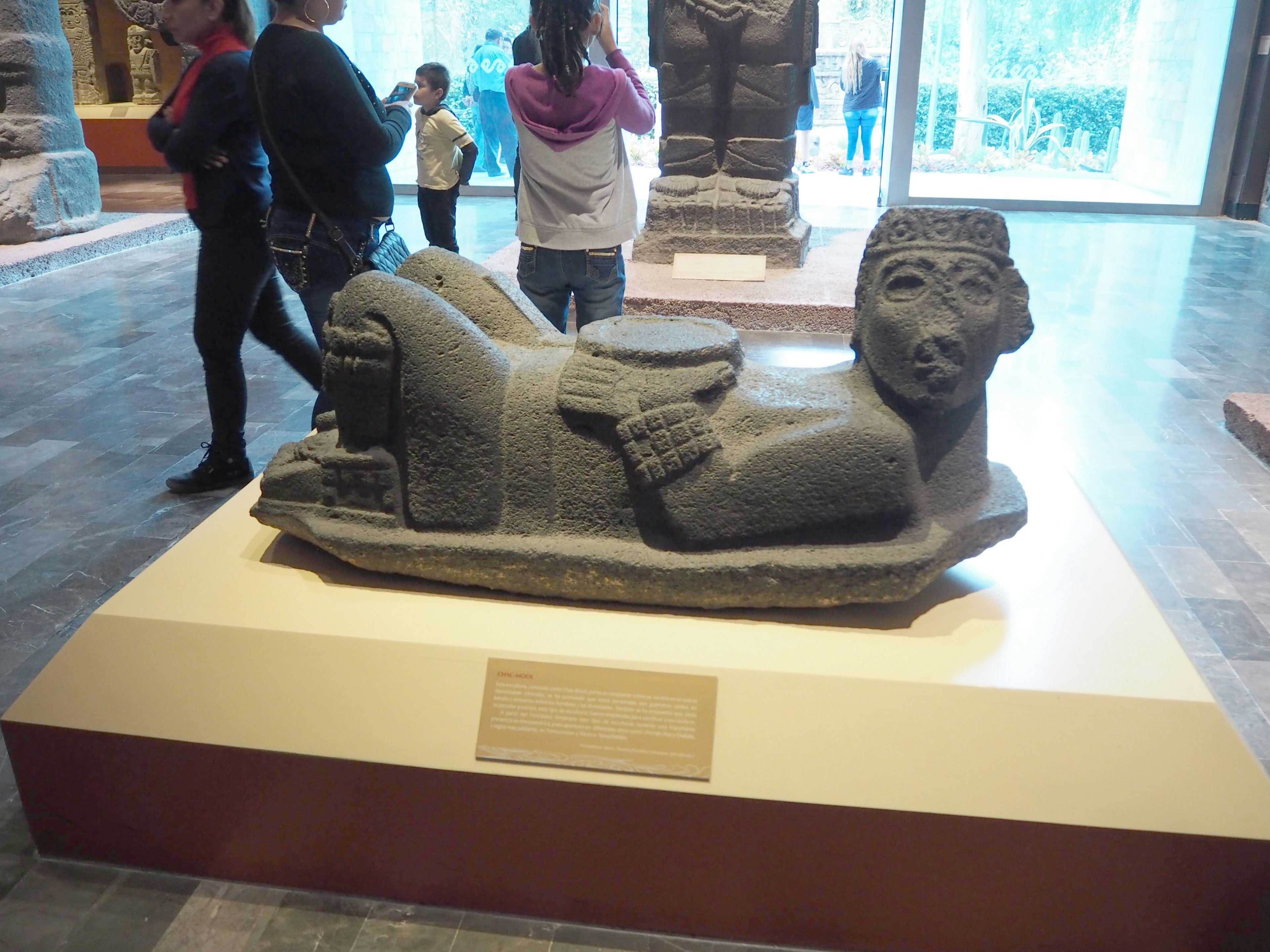 Sculpture of a reclining figure displayed in a museum with visitors