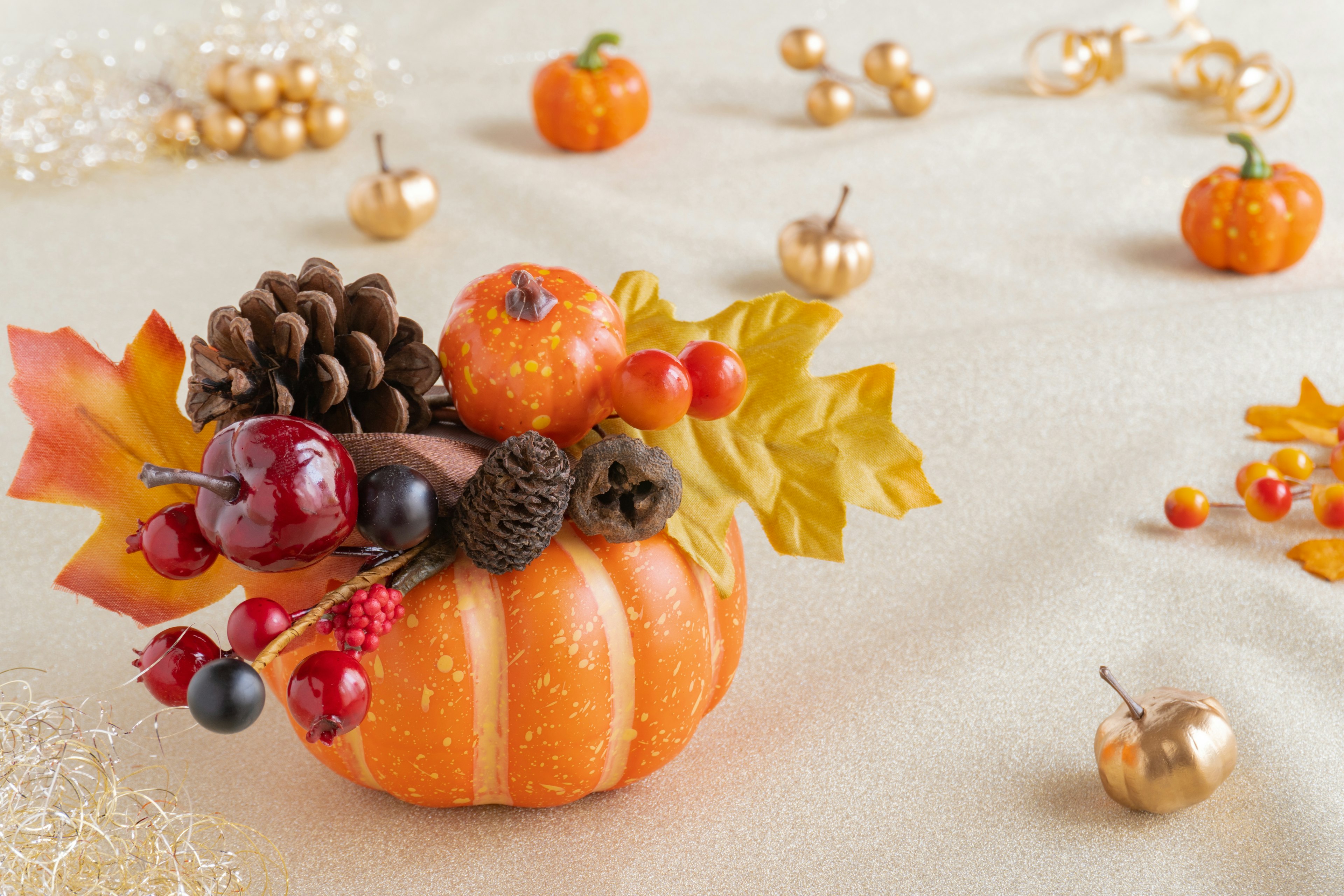 Autumn decoration featuring an orange pumpkin arrangement with pine cones and colorful leaves