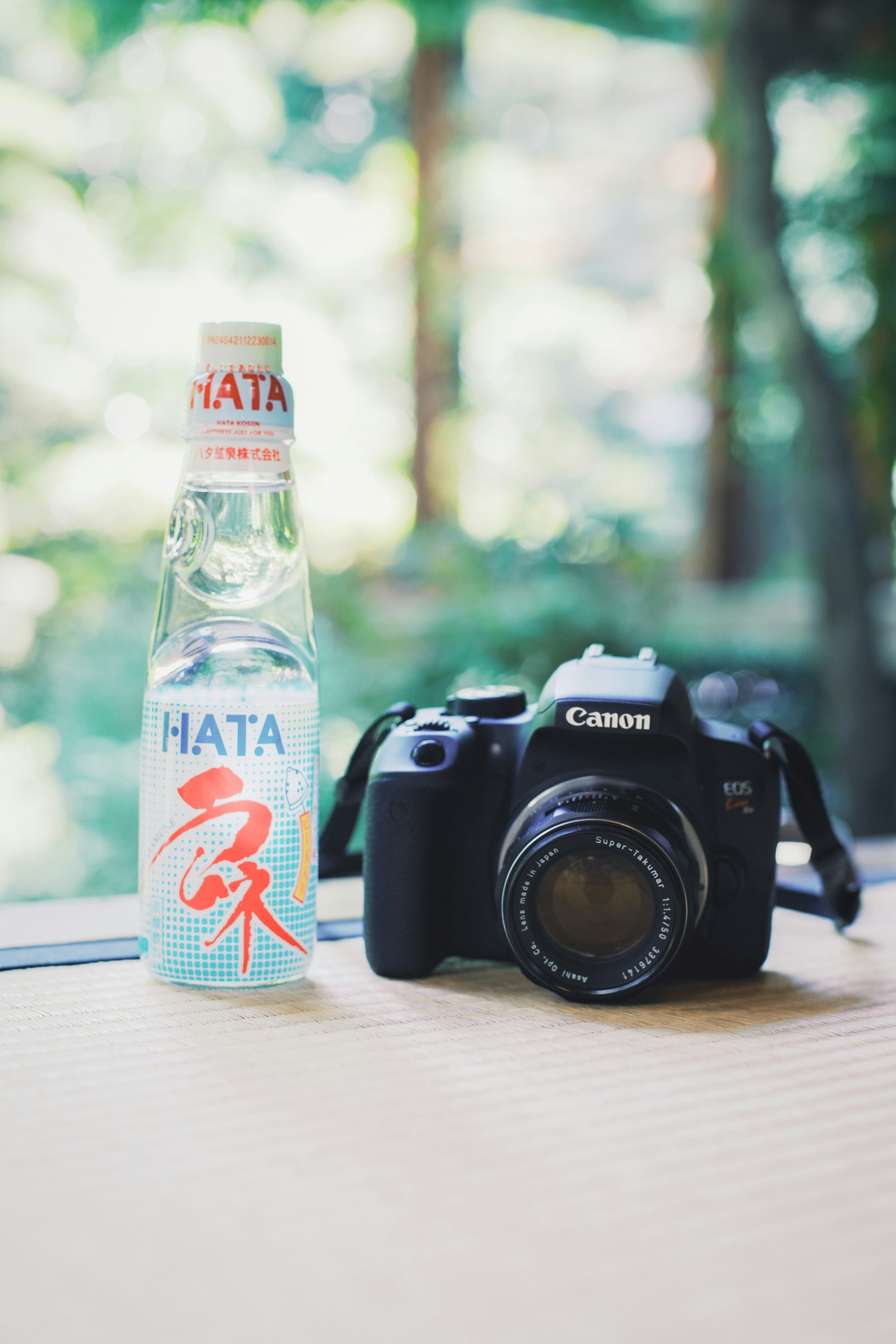 A camera and HATA beverage placed on a windowsill