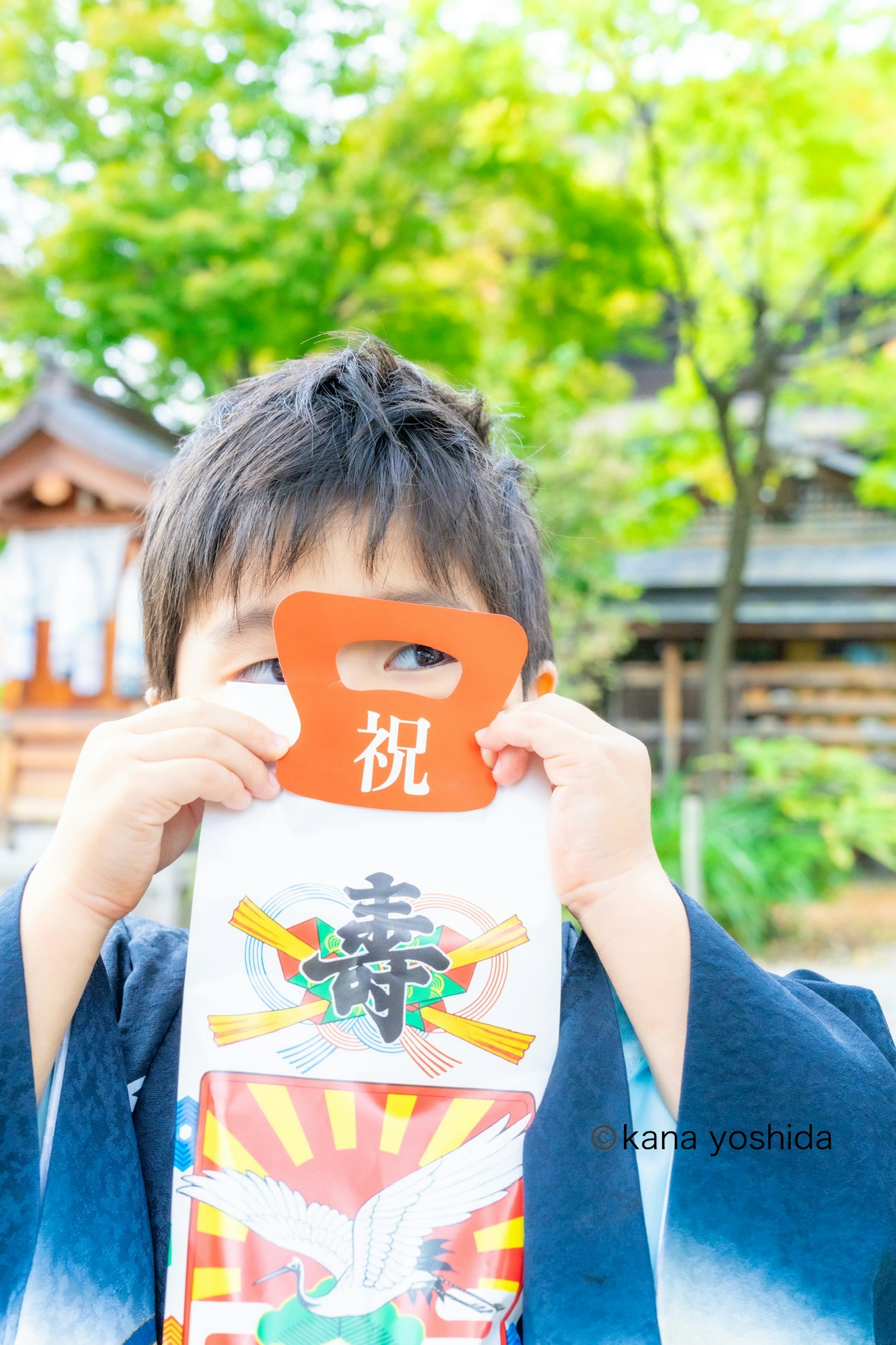 男の子が祝いの御守りを持っている緑の背景の写真