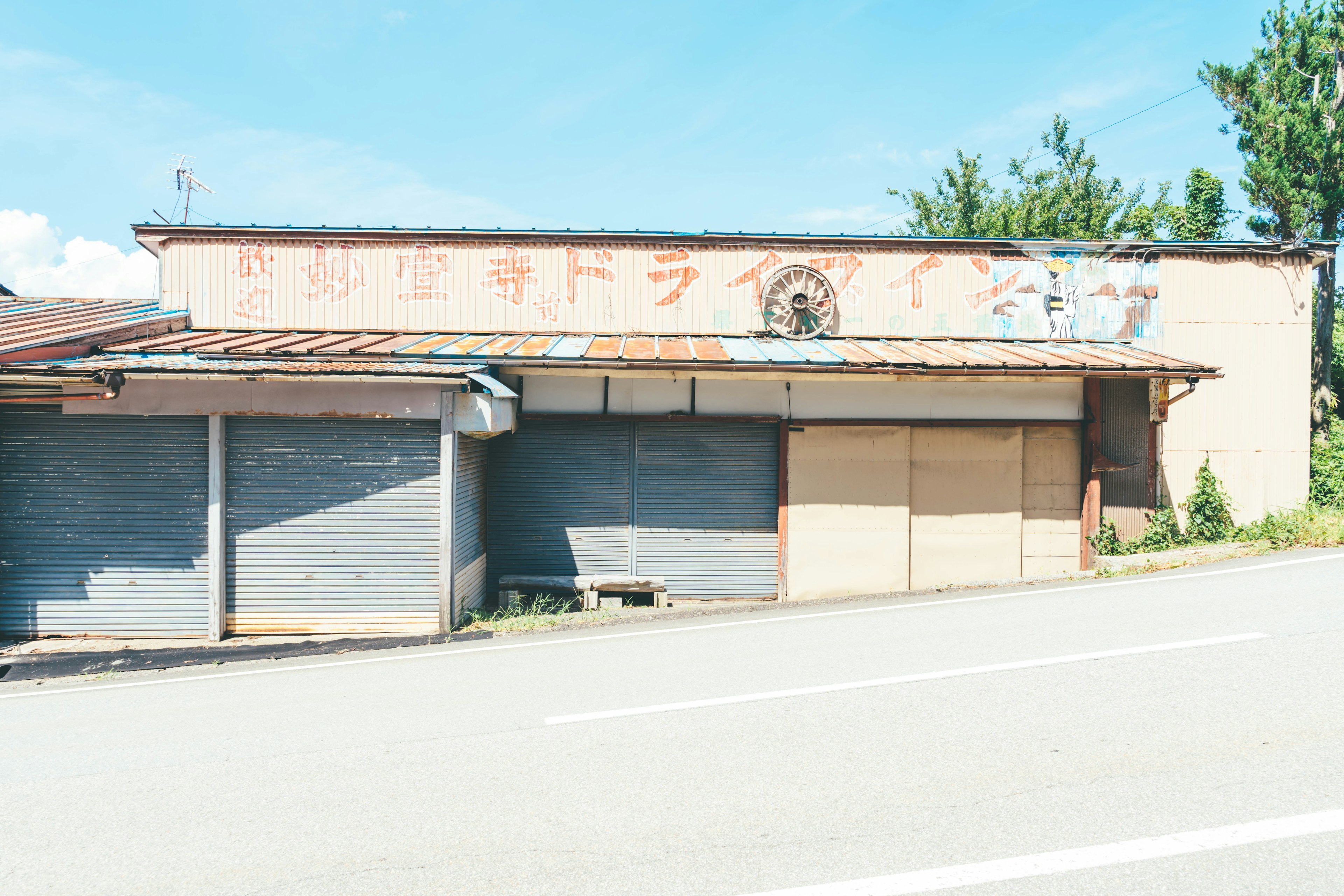 Esterno di un drive-in abbandonato con cielo blu e alberi sullo sfondo