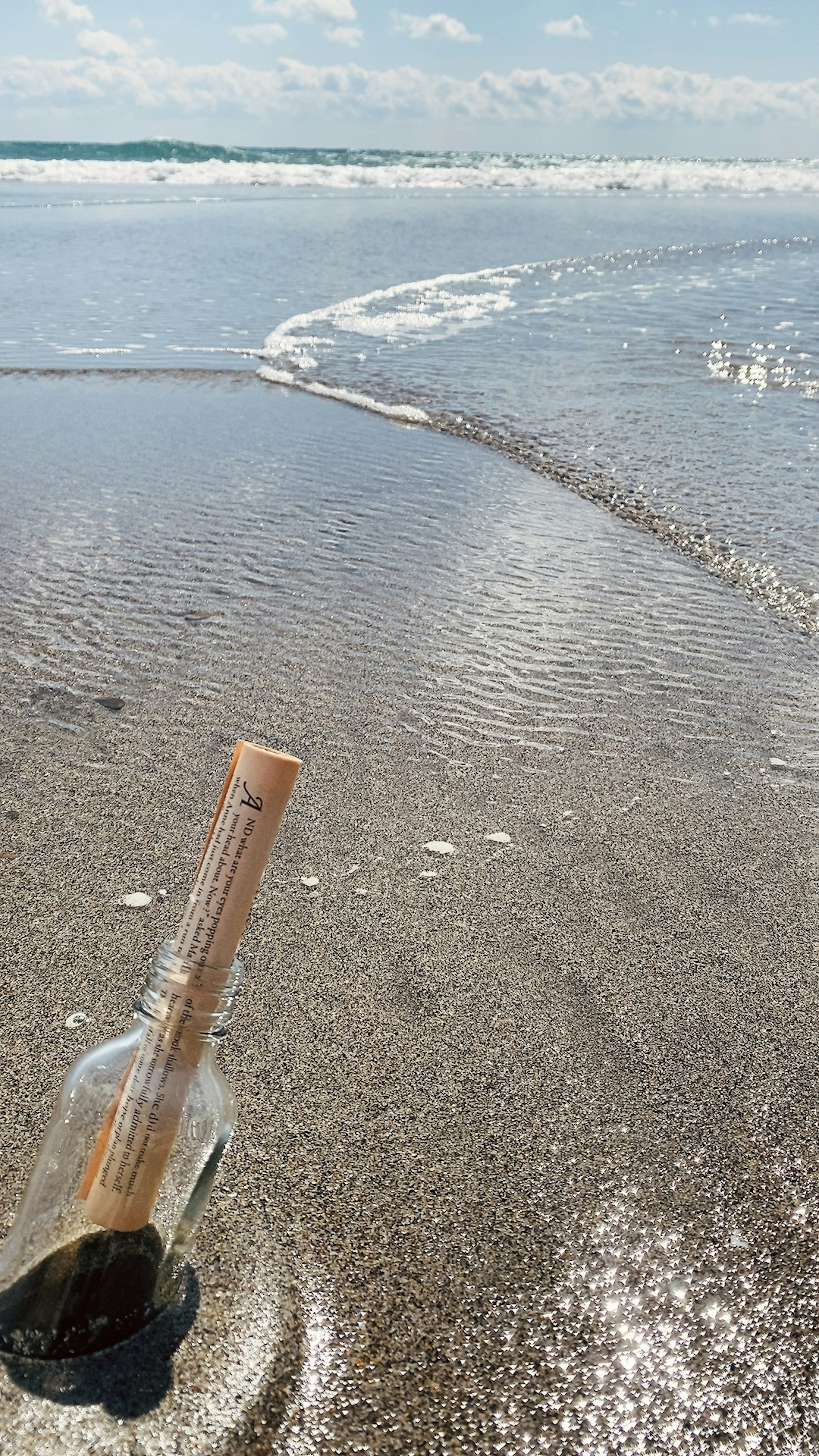 Une bouteille avec un bouchon sur une plage de sable avec des vagues douces