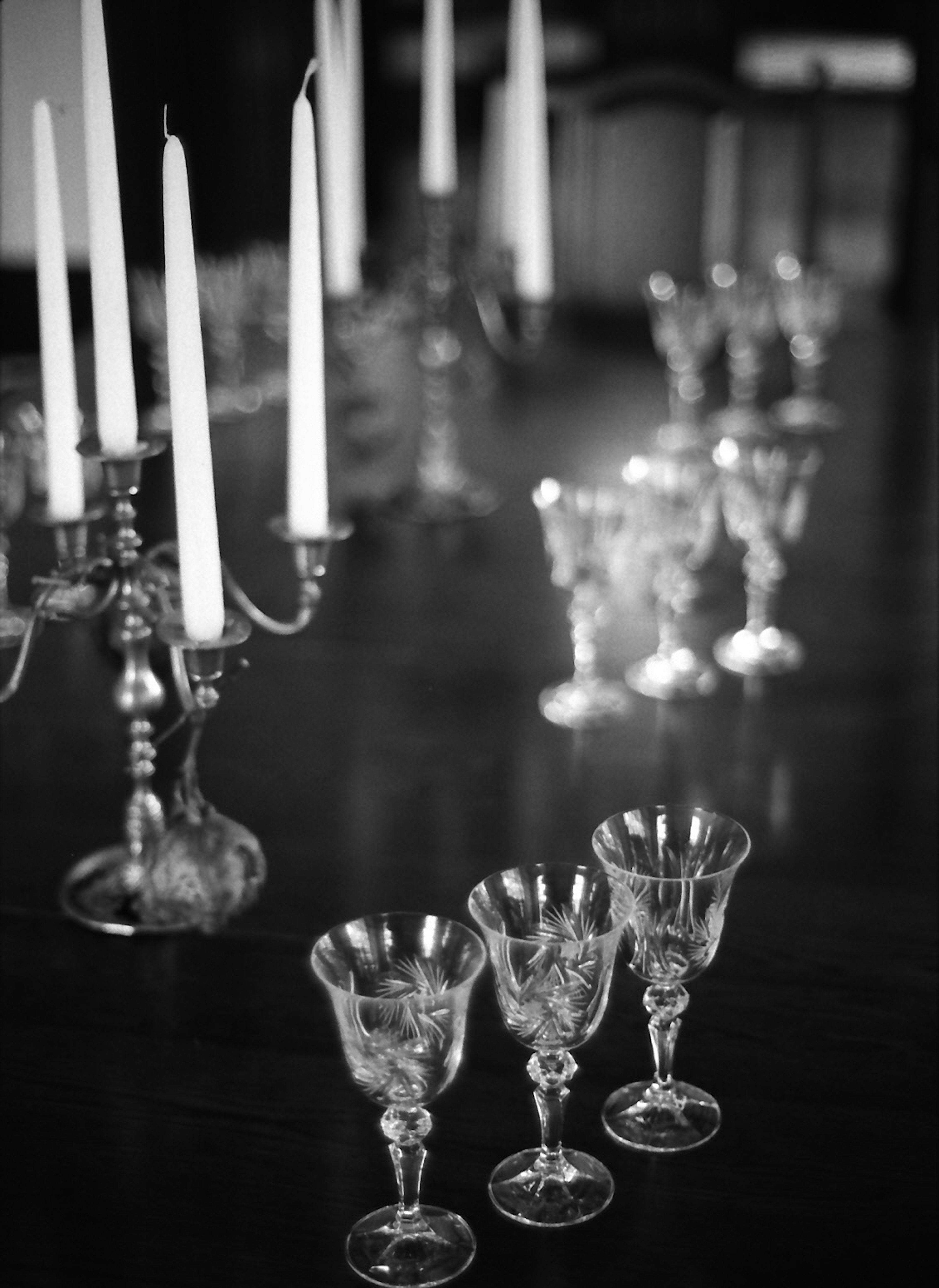 Foto en blanco y negro de una mesa de comedor con velas y copas de cristal