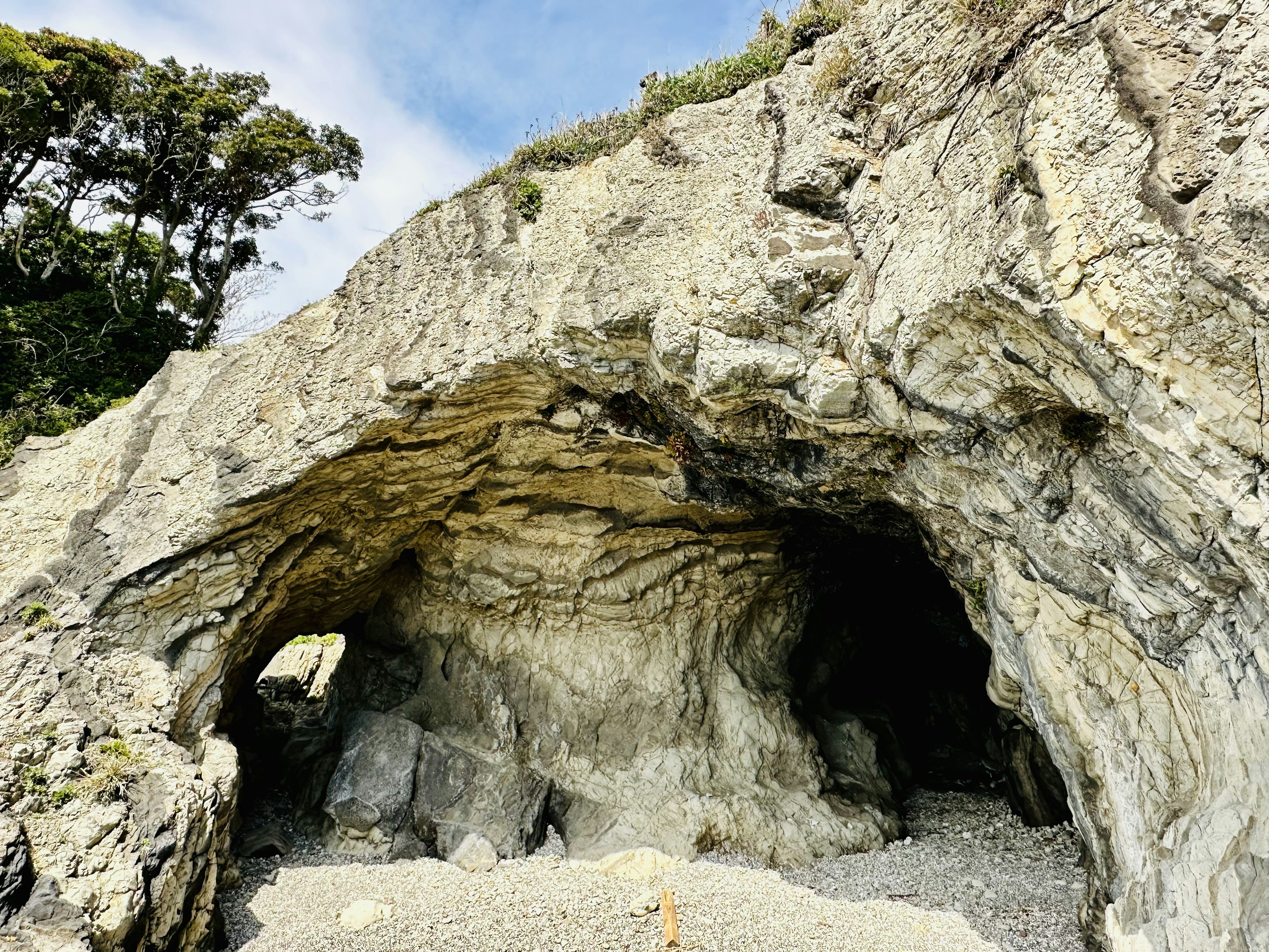 Felsenkeller mit sichtbaren Kalksteinschichten und Küstenlandschaft